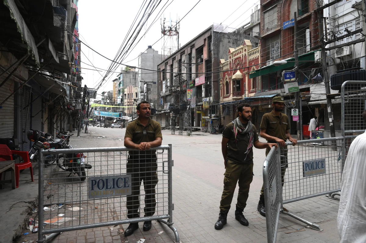 Police stand at a barricade at the entrance of a closed market in Lahore on July 30, 2020. (AFP)