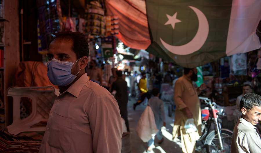 In this picture taken on July 22, 2020, a man wearing a face mask as a preventive measure against the COVID-19 coronavirus shops at the Raja Bazar in Rawalpindi. (AFP)