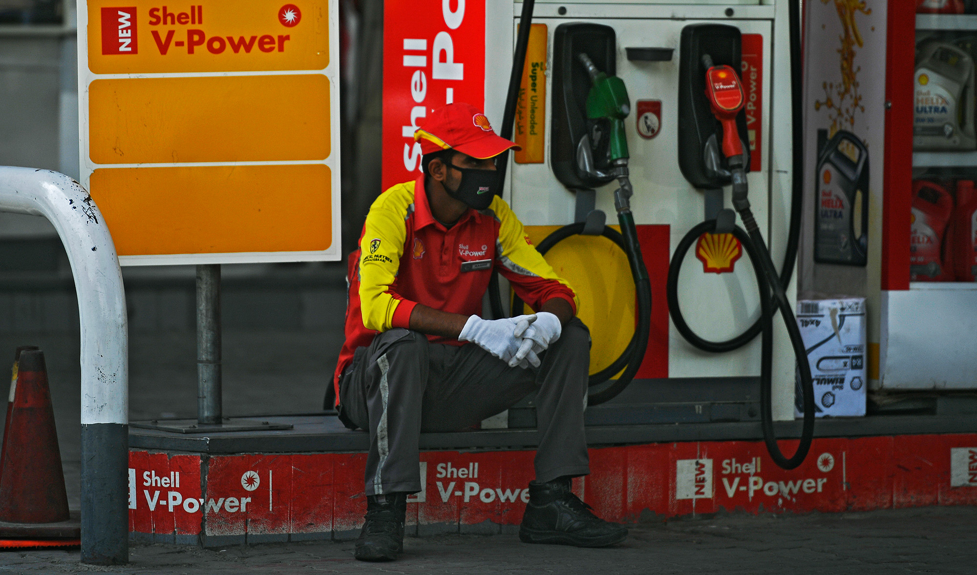 In this file photo, a petrol station worker wearing a facemask waits for customers while sitting next to a petrol pump during a government-imposed nationwide lockdown as a preventive measure against the COVID-19 coronavirus, in Islamabad on April 22, 2020. (AFP)