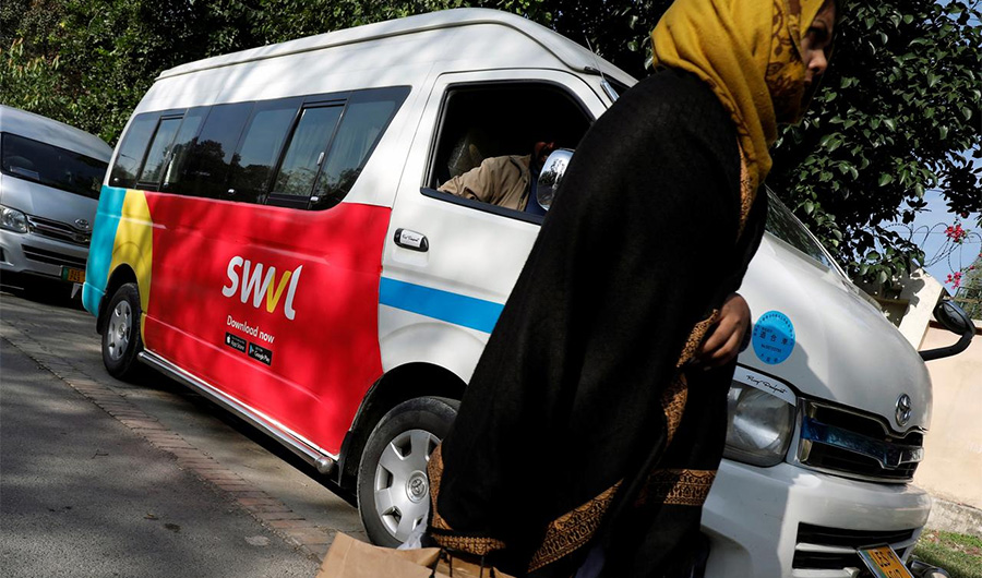 A woman walks past a vehicle with a logo of the Egyptian transport technology start-up Swvl, parked along a road in Islamabad, Pakistan, on November 11, 2019. (REUTERS)