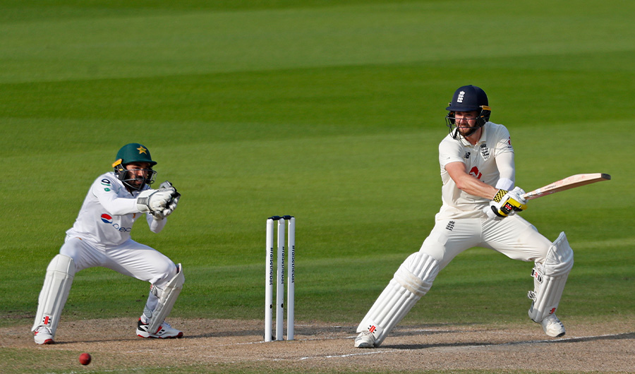 England's Chris Woakes (R) plays a shot as Pakistan's Mohammad Rizwan keeps wicket (L) during play on the fourth day of the first Test cricket match between England and Pakistan at Old Trafford in Manchester, north-west England on August 8, 2020. (AFP)