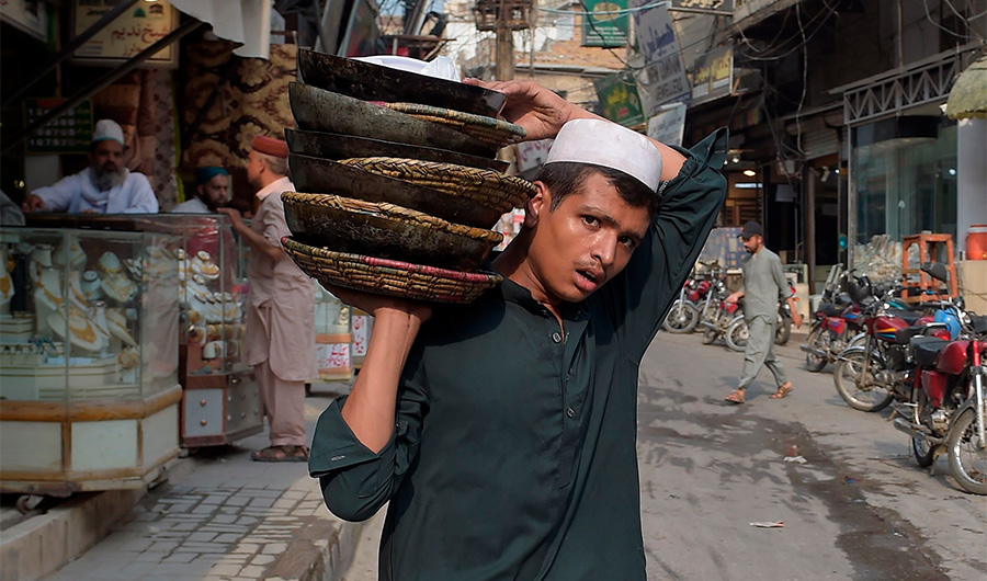 A restaurant delivery guy holds empty crockeries at a market in Rawalpindi on August 8, 2020, after government announced it would be lifting most of the country's remaining coronavirus restrictions after seeing new cases drop for several weeks. (AFP)