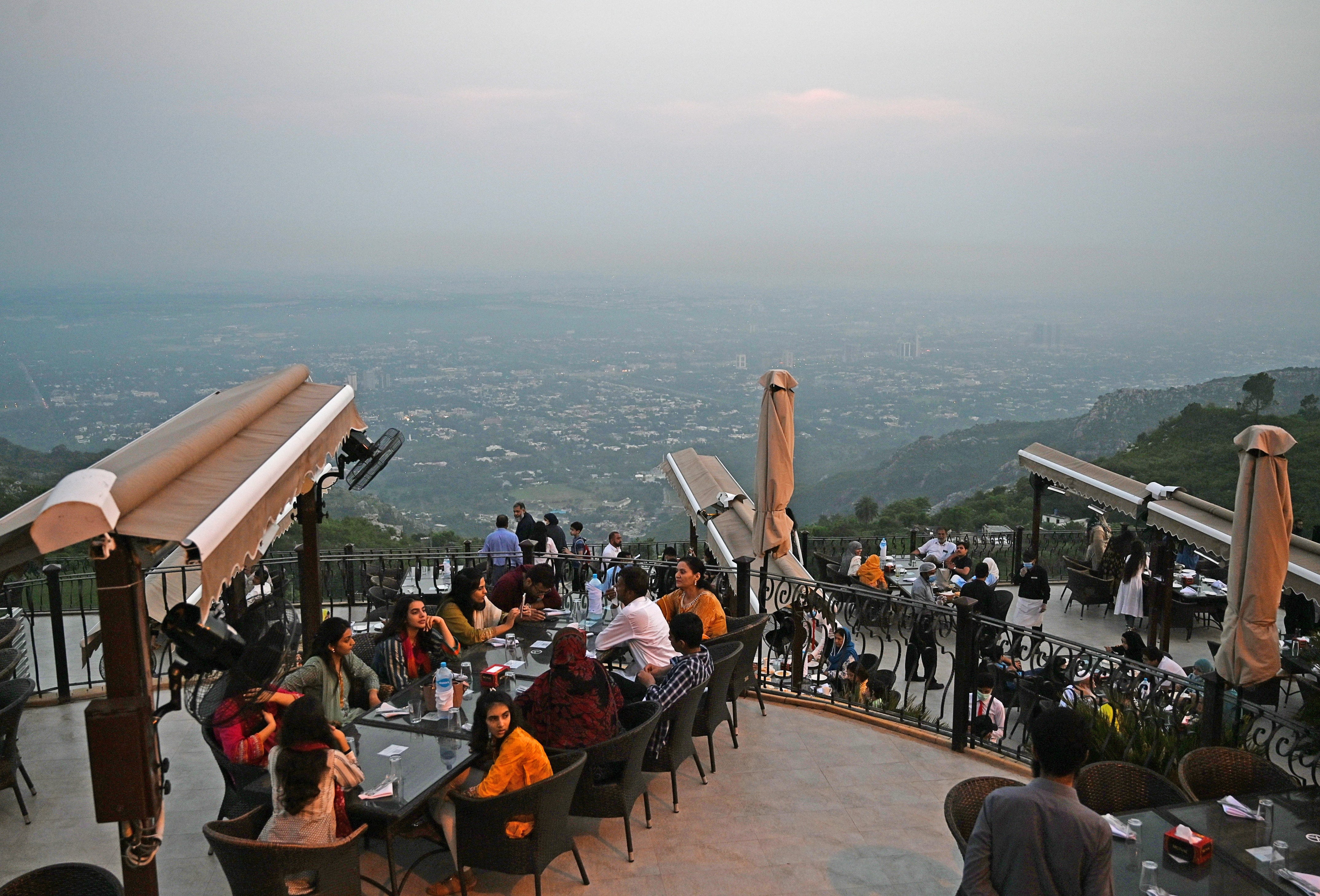 People wait for food on top of a restaurant on Margalla Hills in Islamabad on August 10, 2020, after government announced it would be lifting most of the country's remaining coronavirus restrictions after seeing new cases drop for several weeks. (AFP)