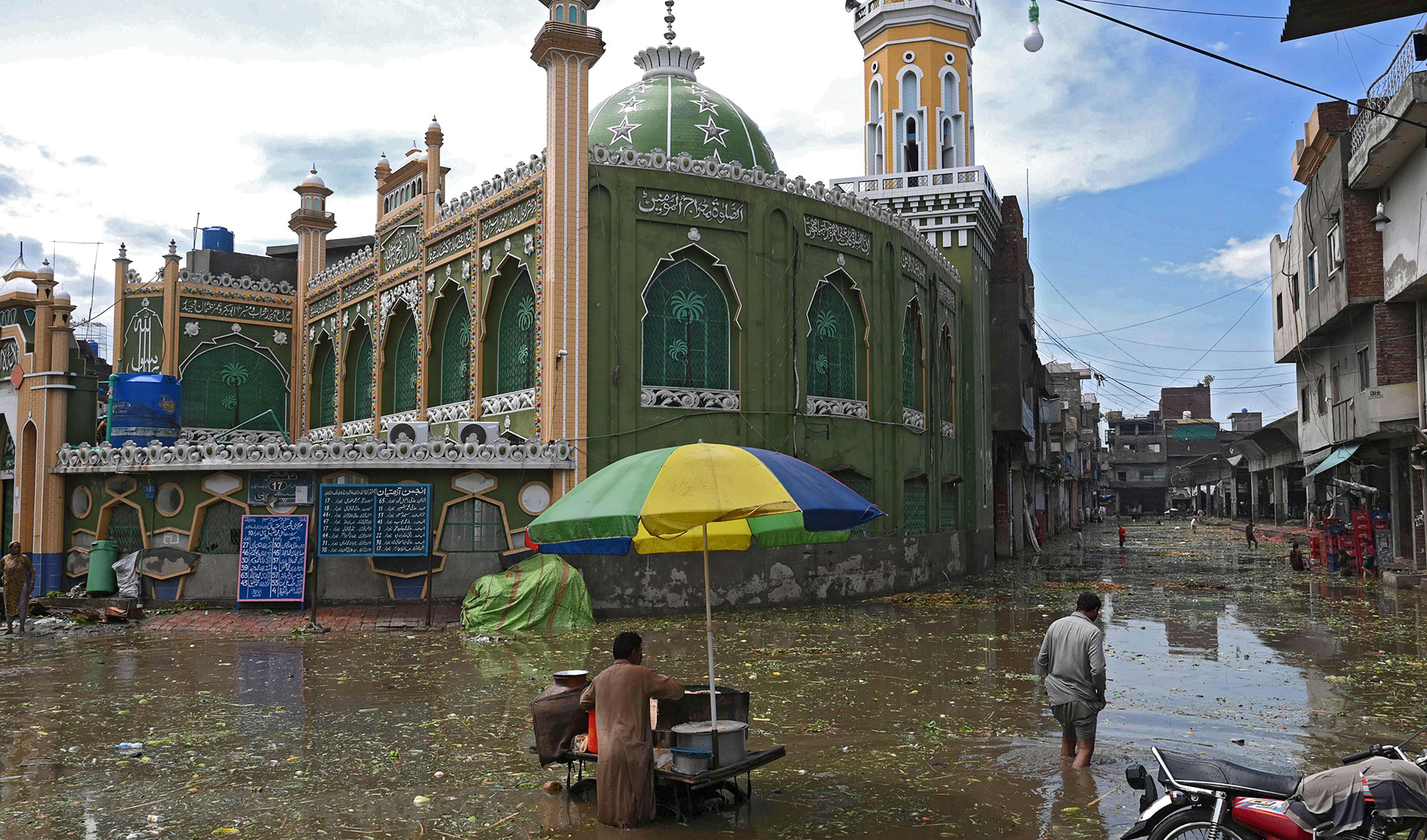 A food vendor waits for customers at a flooded area after heavy monsoon rains in Lahore on Aug. 10, 2020. (AFP)