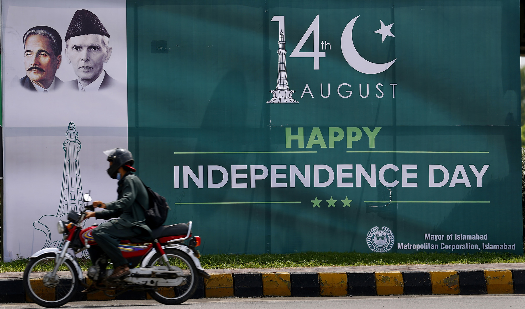 A motorcyclist rides past a Happy Independence Day billboard along a roadside for Pakistan Independence Day celebrations in Islamabad on Aug. 13, 2020. (AP)