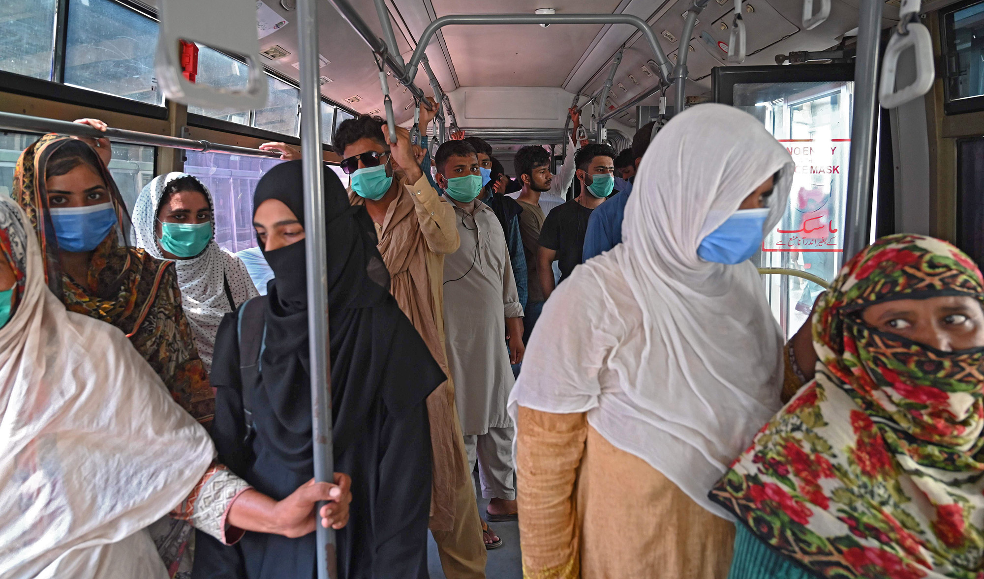 Commuters wearing face masks travel in a Metrobus in Lahore on August 12, 2020 after Pakistan's government announced it would be lifting most of the country's remaining coronavirus restrictions after seeing new cases drop for several weeks. (AFP)