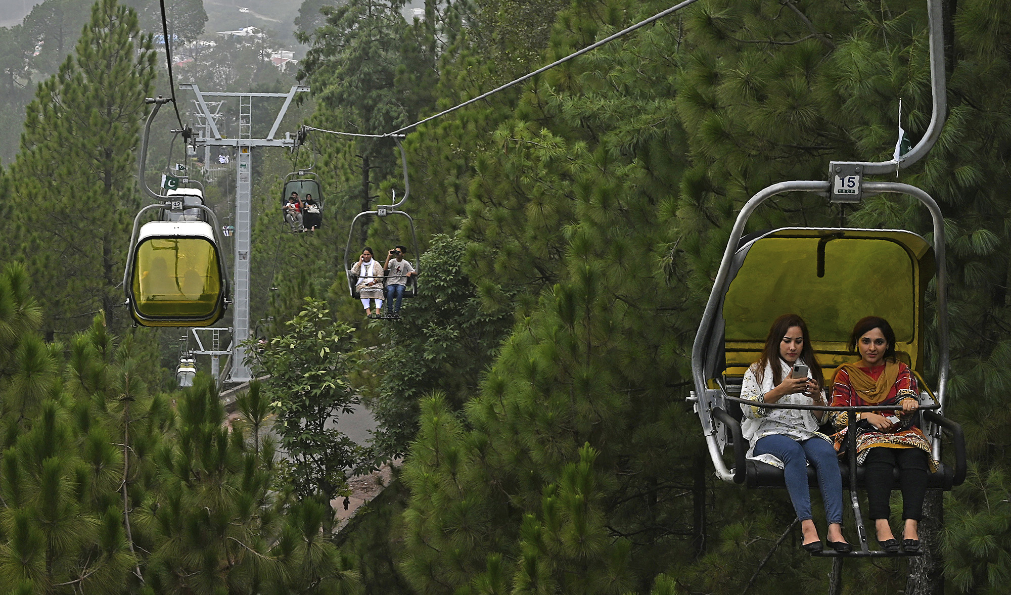 Tourists sit on chairlifts at the Patriata Resort near Murree, some 65 km form Islamabad on Aug. 16, 2020, after the government announced most of the country's remaining restrictions would be lifted following the drop in COVID-19 coronavirus new cases for several weeks. (AFP)