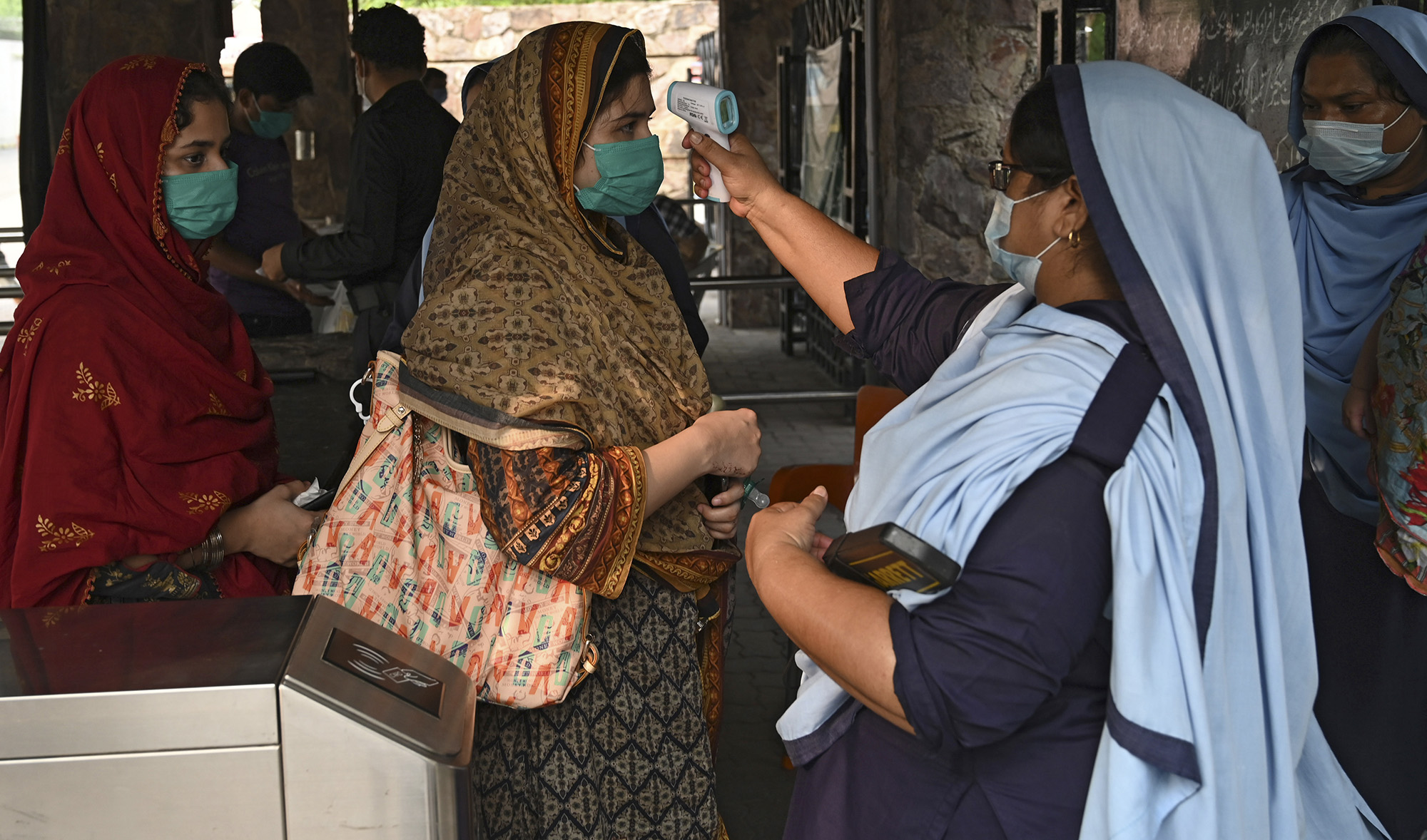 An official, right, checks the body temperature of a woman before entering at a Zoo in Lahore on Aug. 11, 2020. (AFP)