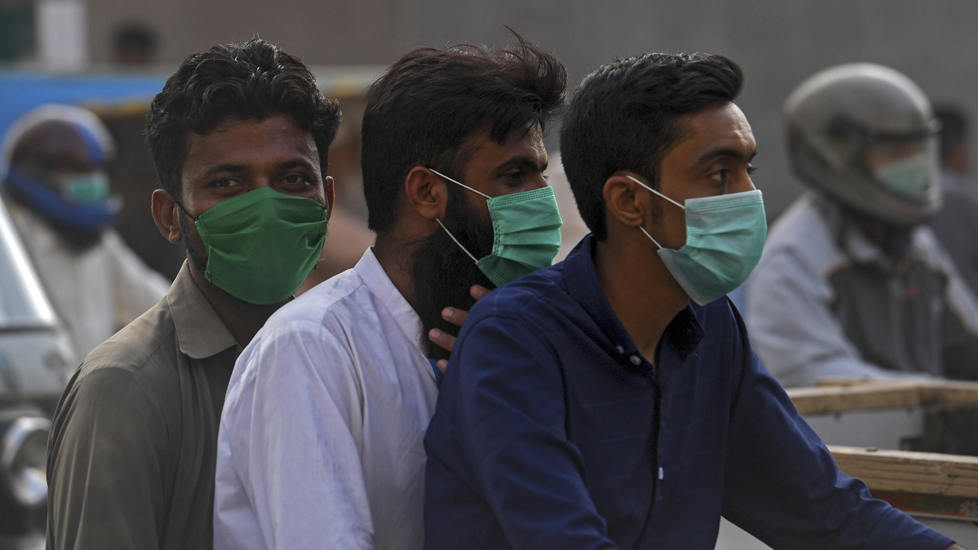 Commuters wearing facemasks, to stay protected from COVID-19 coronavirus, ride on a bike on a street in Karachi on June 22, 2020. (AFP/File)