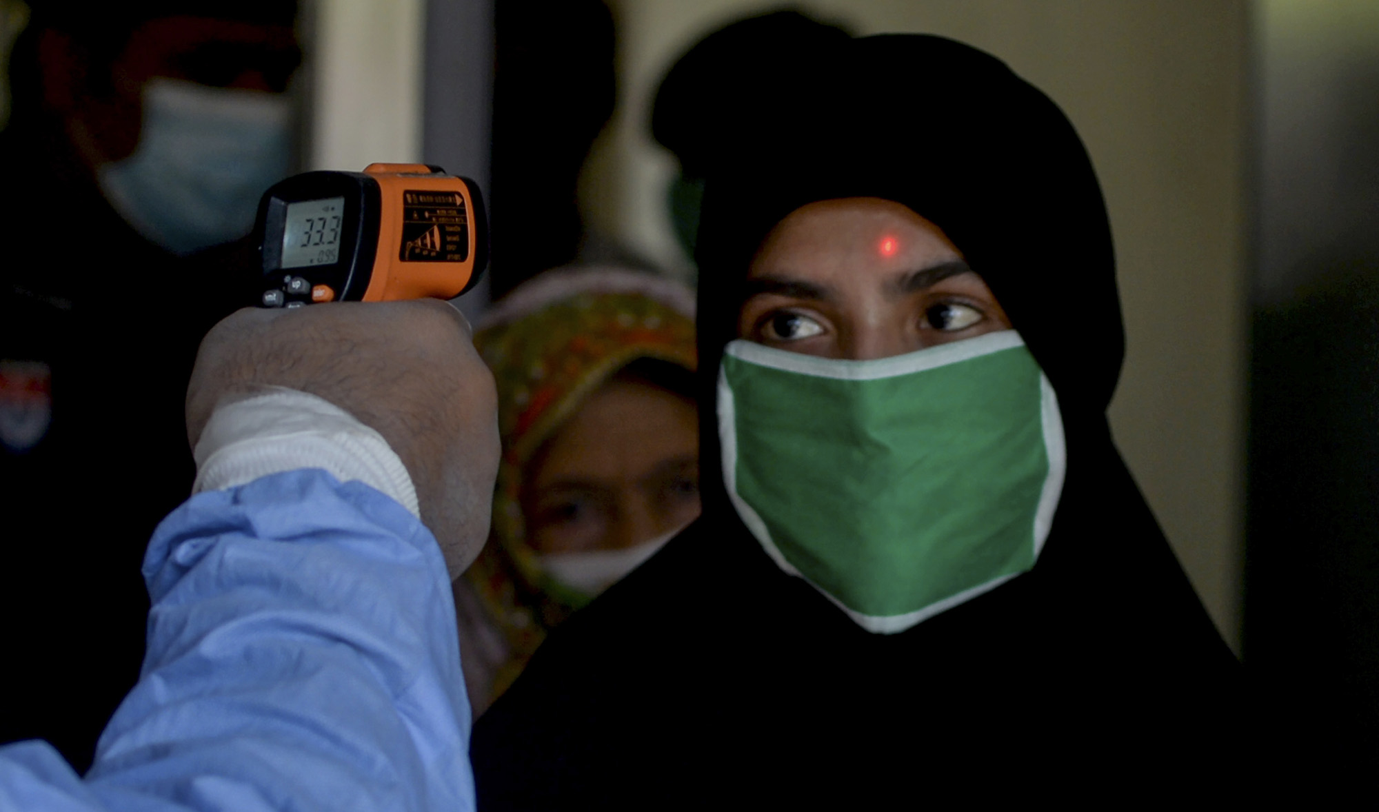 A railway official checks body temperature of a passenger before boarding a train at the Karachi cantonment railway station as a preventive measure against the COVID-19 coronavirus, in Karachi on May 20, 2020. (AFP/File)