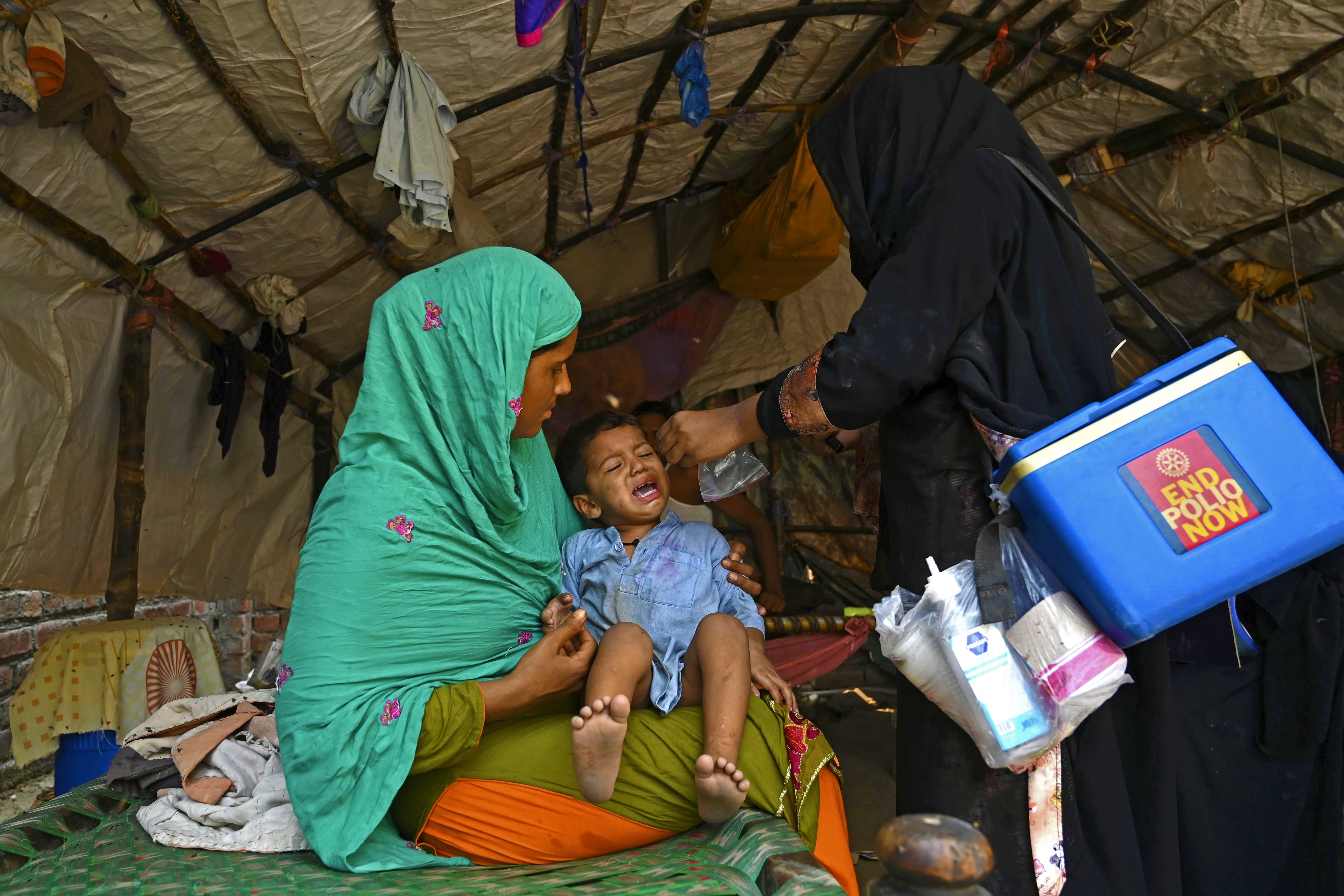 A health worker (R) administers polio vaccine drops to a child during a polio vaccination door-to-door campaign in Lahore on August 16, 2020. (AFP)