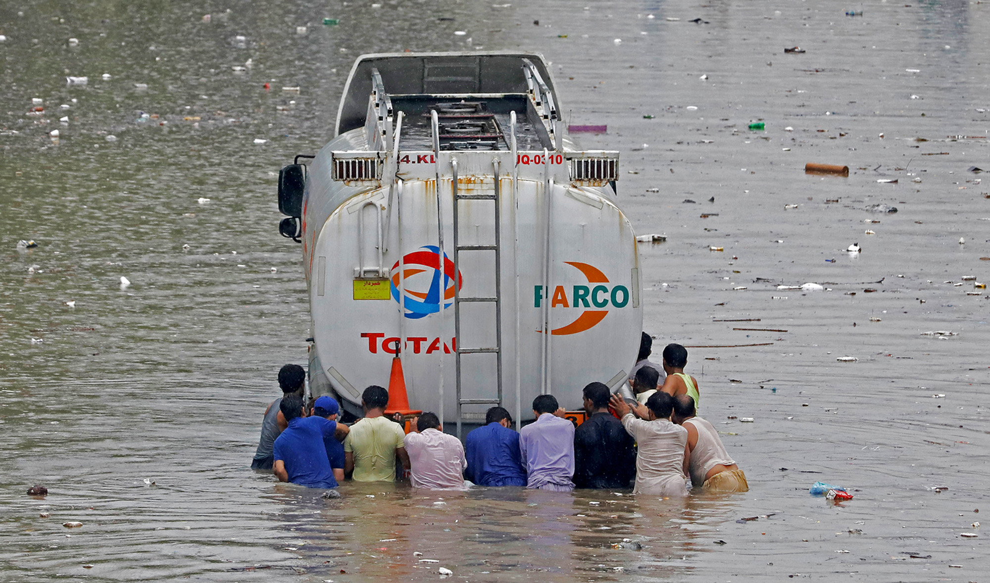 Men push a truck through a flooded road during monsoon rain, as the outbreak of the coronavirus disease (COVID-19) continues, in Karachi on Aug. 25, 2020. (REUTERS)