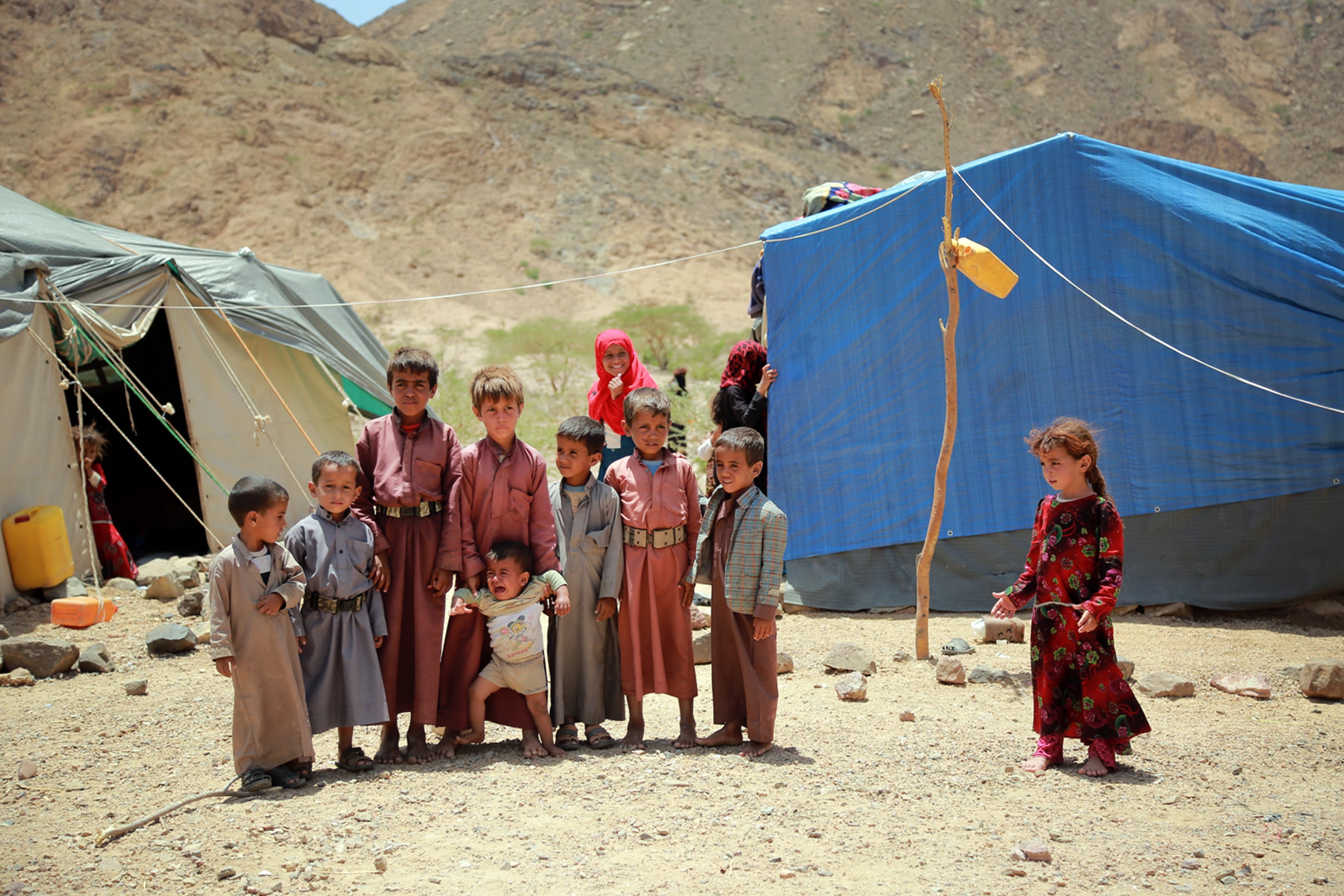 Yemeni children stand outside a tent at a makeshift camp for internally displaced persons after they were forced to flee their homes due to the ongoing fighting in the country, in the Nehm region, west of Ma'rib city, on May 8, 2016. (AFP/File)