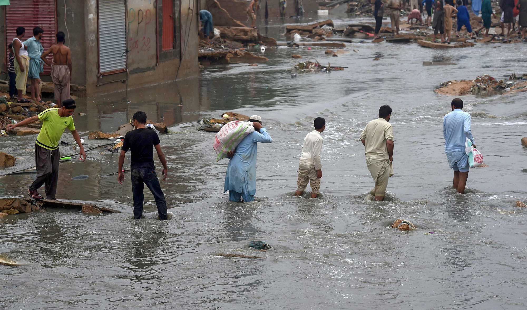 People wade through a flooded residential area after heavy monsoon rains in Pakistan's port city of Karachi on Aug. 27, 2020. (AFP)