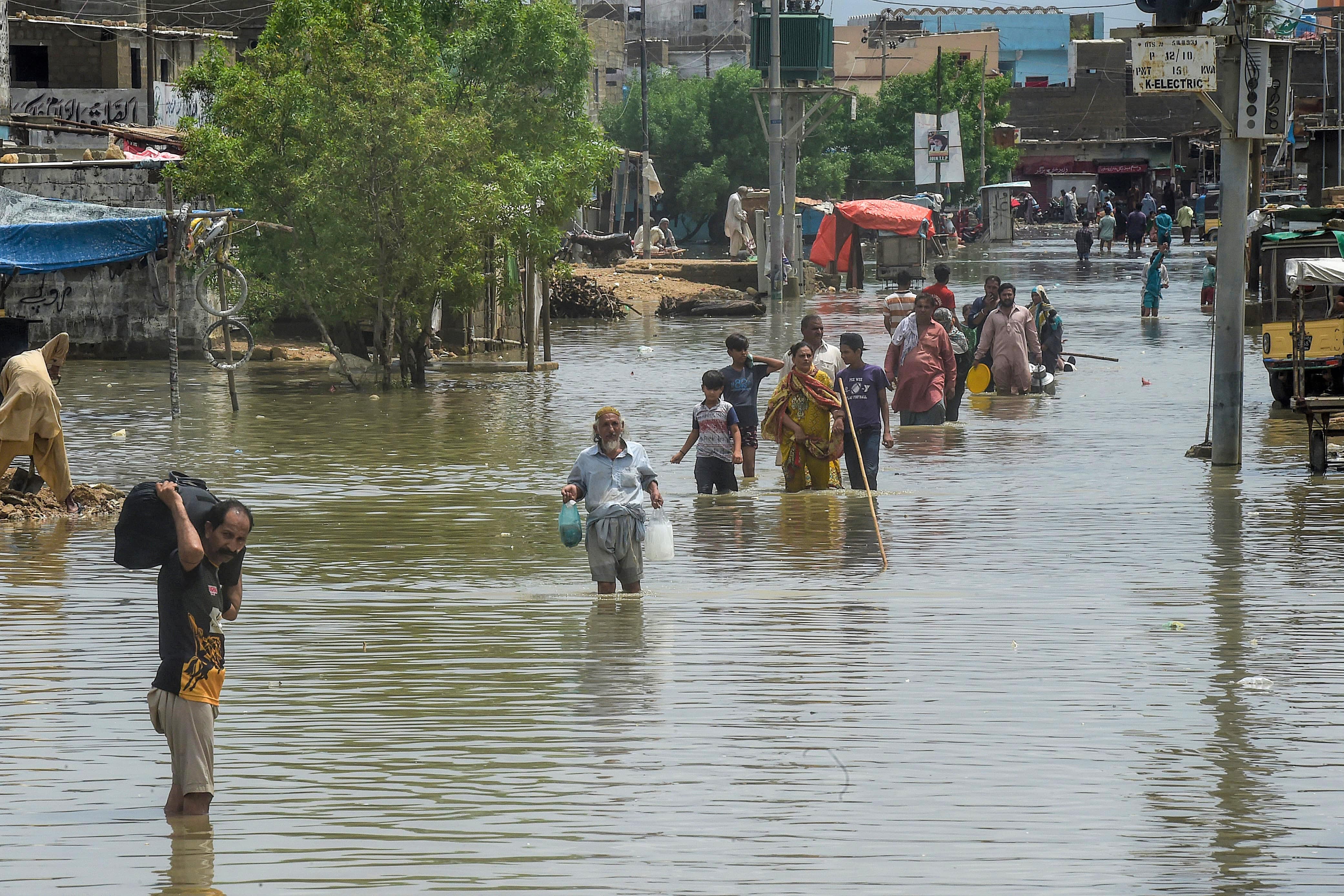 People wade through a flooded residential area after heavy monsoon rains triggered floods in Pakistan's port city of Karachi on August 28, 2020. (AFP)