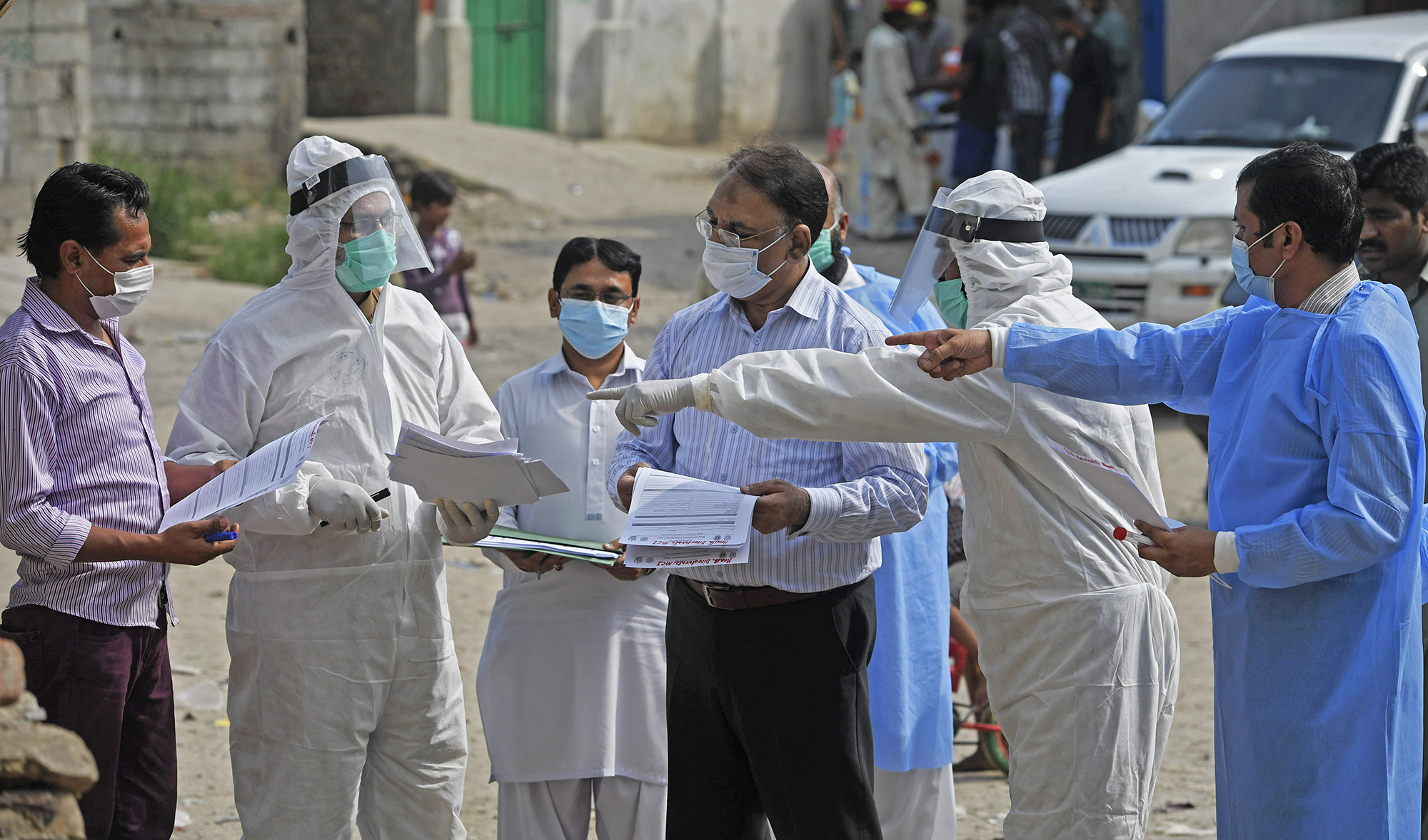 Health officials wearing Personal Protective Equipment (PPE) hold medical records collected form residents after taking samples for COVID-19 coronavirus during a door-to-door screening and testing operation at a slum area in Islamabad on June 30, 2020. (AFP/File)