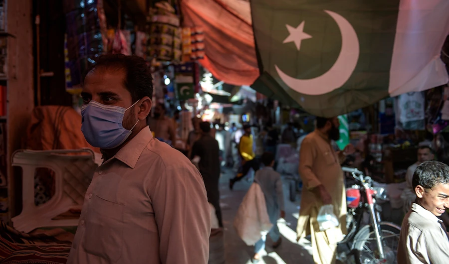 In this picture taken on July 22, 2020, a man wearing a face mask as a preventive measure against the COVID-19 coronavirus shops at the Raja Bazar in Rawalpindi. (AFP)