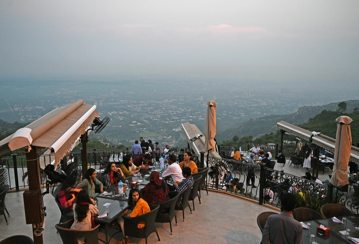 People wait for food on top of a restaurant on Margalla Hills in Islamabad on August 10, 2020, after government announced it would be lifting most of the country's remaining coronavirus restrictions after seeing new cases drop for several weeks. (AFP)