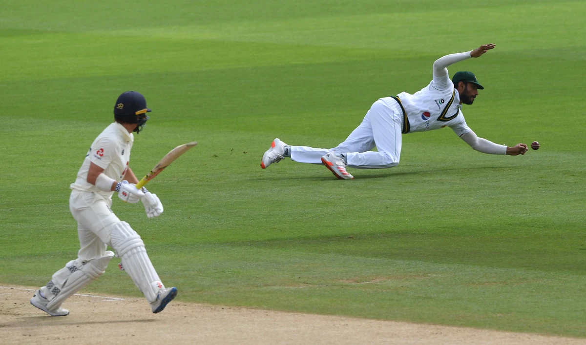 Pakistan's Shan Masood, right, dives to field the ball after a shot played by England's Rory Burns, left, during the first day of the third cricket Test match between England and Pakistan, at the Ageas Bowl in Southampton, England on Aug. 21, 2020. (Pool via AP)