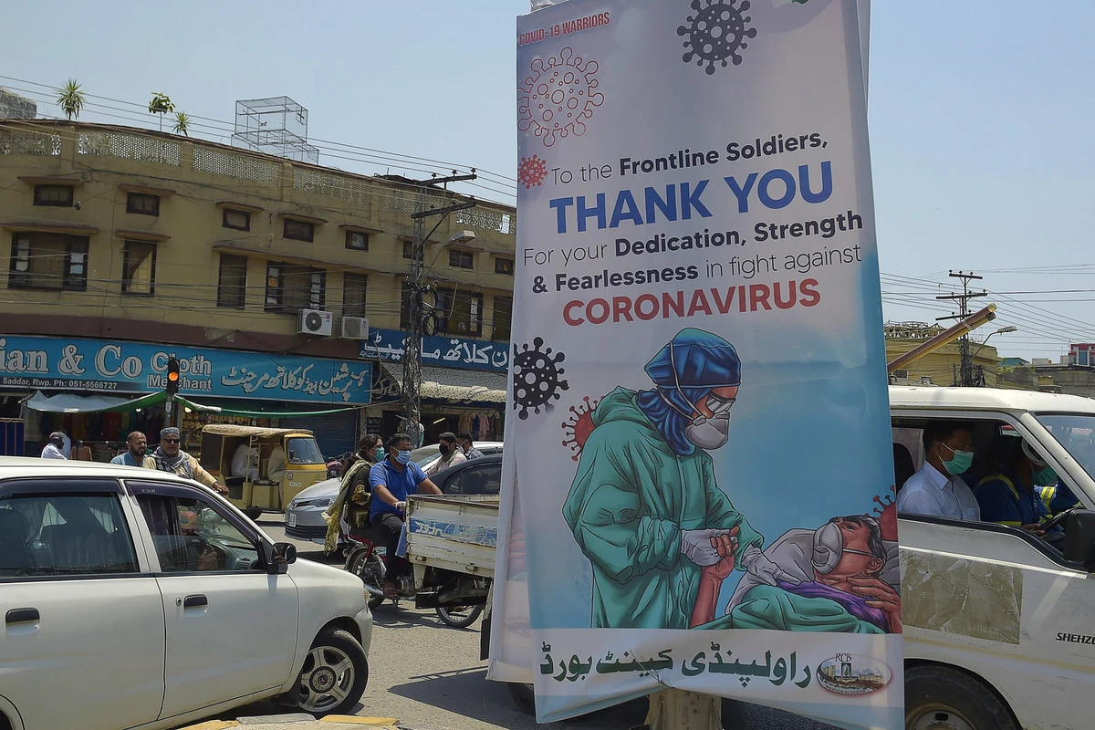 Commuters ride past a poster that shows gratitude to frontline workers fighting against the spread of the COVID-19 coronavirus, in Rawalpindi on June 30, 2020. (AFP)