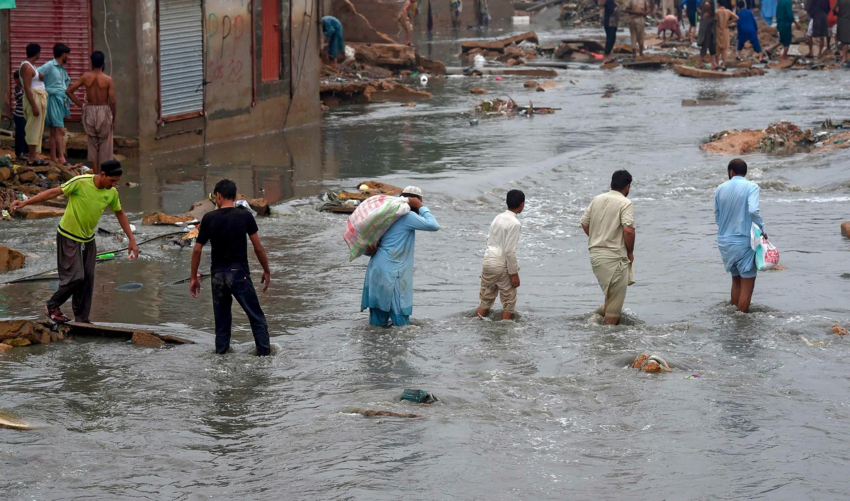 People wade through a flooded residential area after heavy monsoon rains in Pakistan's port city of Karachi on Aug. 27, 2020. (AFP)