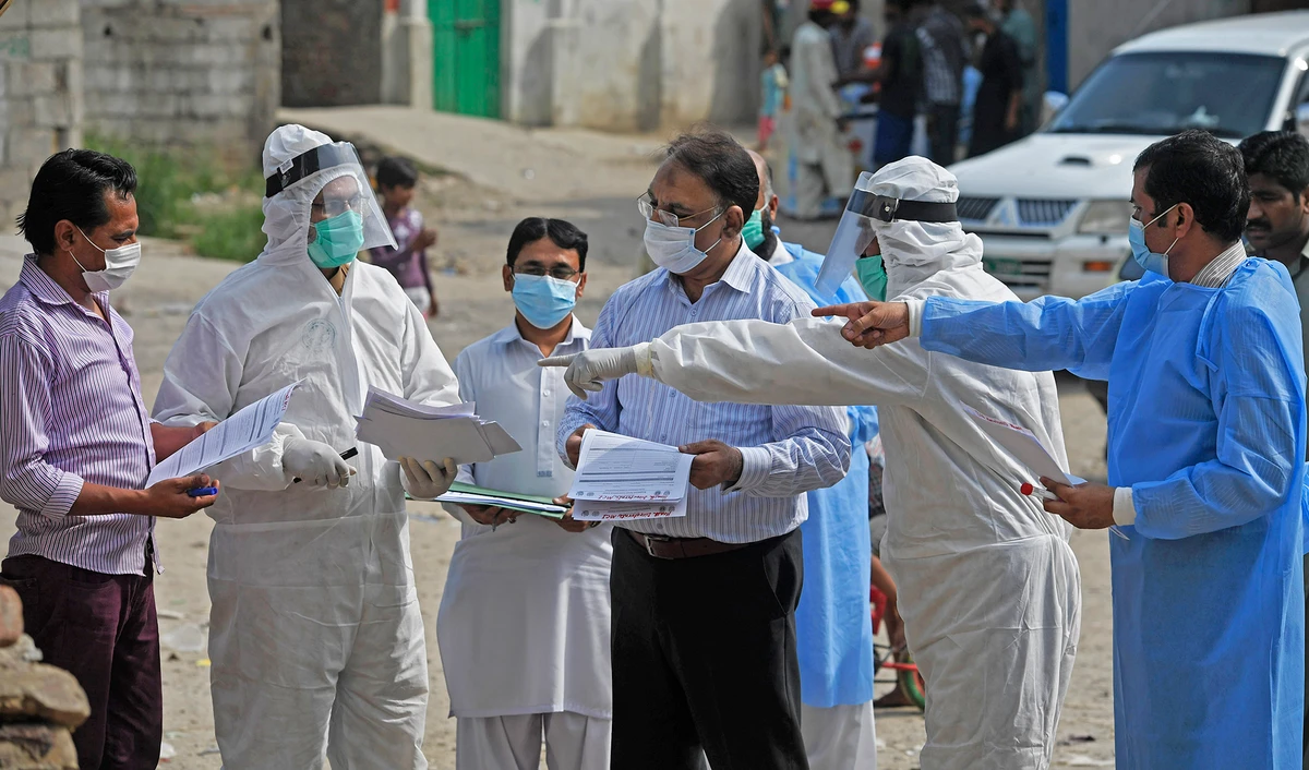 Health officials wearing Personal Protective Equipment (PPE) hold medical records collected form residents after taking samples for COVID-19 coronavirus during a door-to-door screening and testing operation at a slum area in Islamabad on June 30, 2020. (AFP/File)