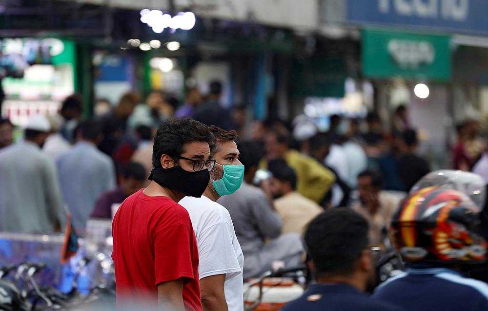Men wearing protective masks walk along a market, as the Covid-19 outbreak continues, in Karachi, Pakistan August 31, 2020. (Reuters)