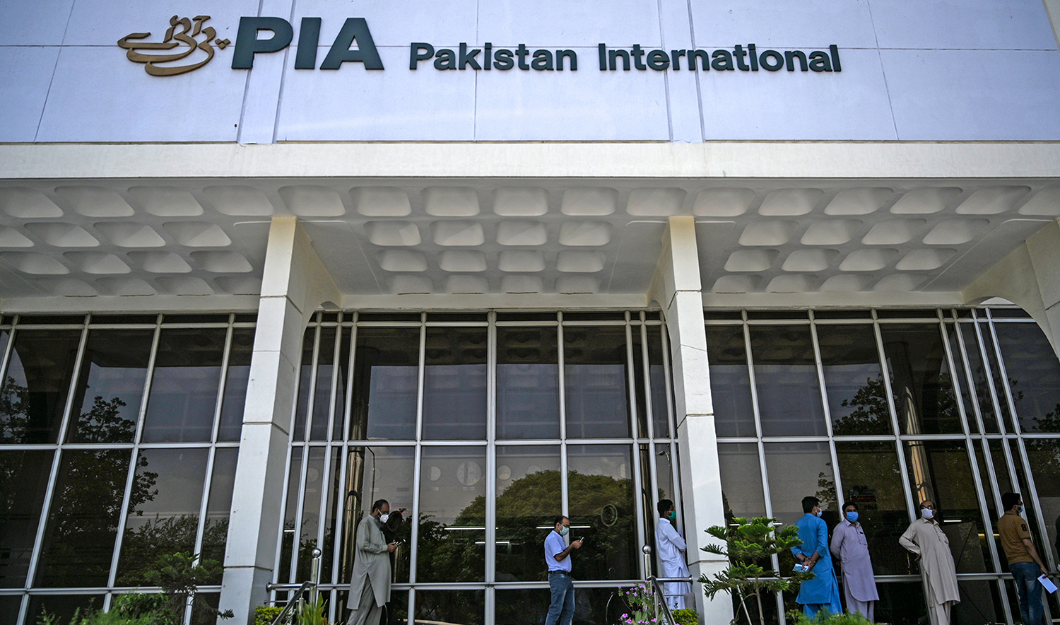 People stand in queue as they wait their turn to buy flight tickets outside Pakistan International Airlines (PIA) office in Islamabad on July 1, 2020. (AFP/File)