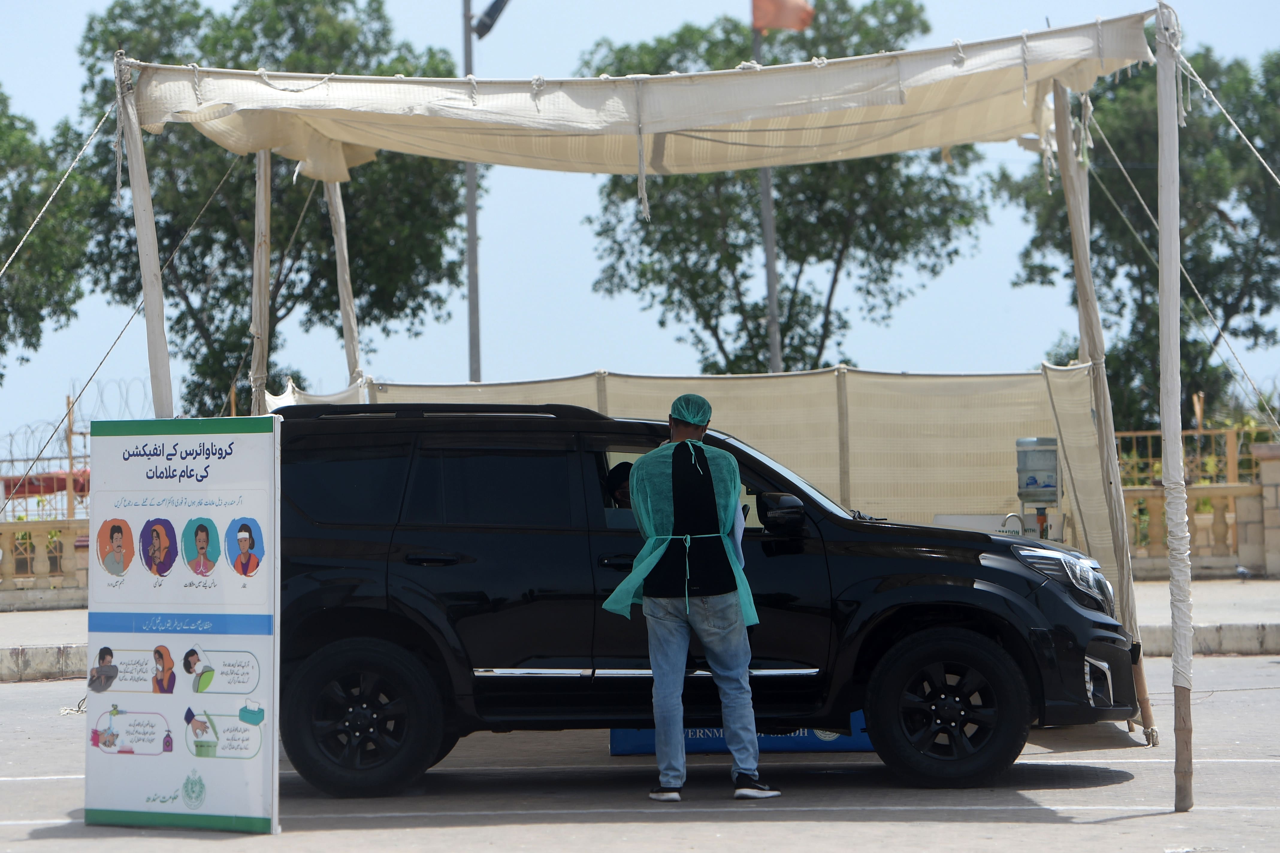 In this picture taken on June 2, 2020 a health official wearing protective gear prepares to take a sample from a man sitting in a car at a drive-through screening and testing facility for COVID-19 in Karachi. (AFP/File)