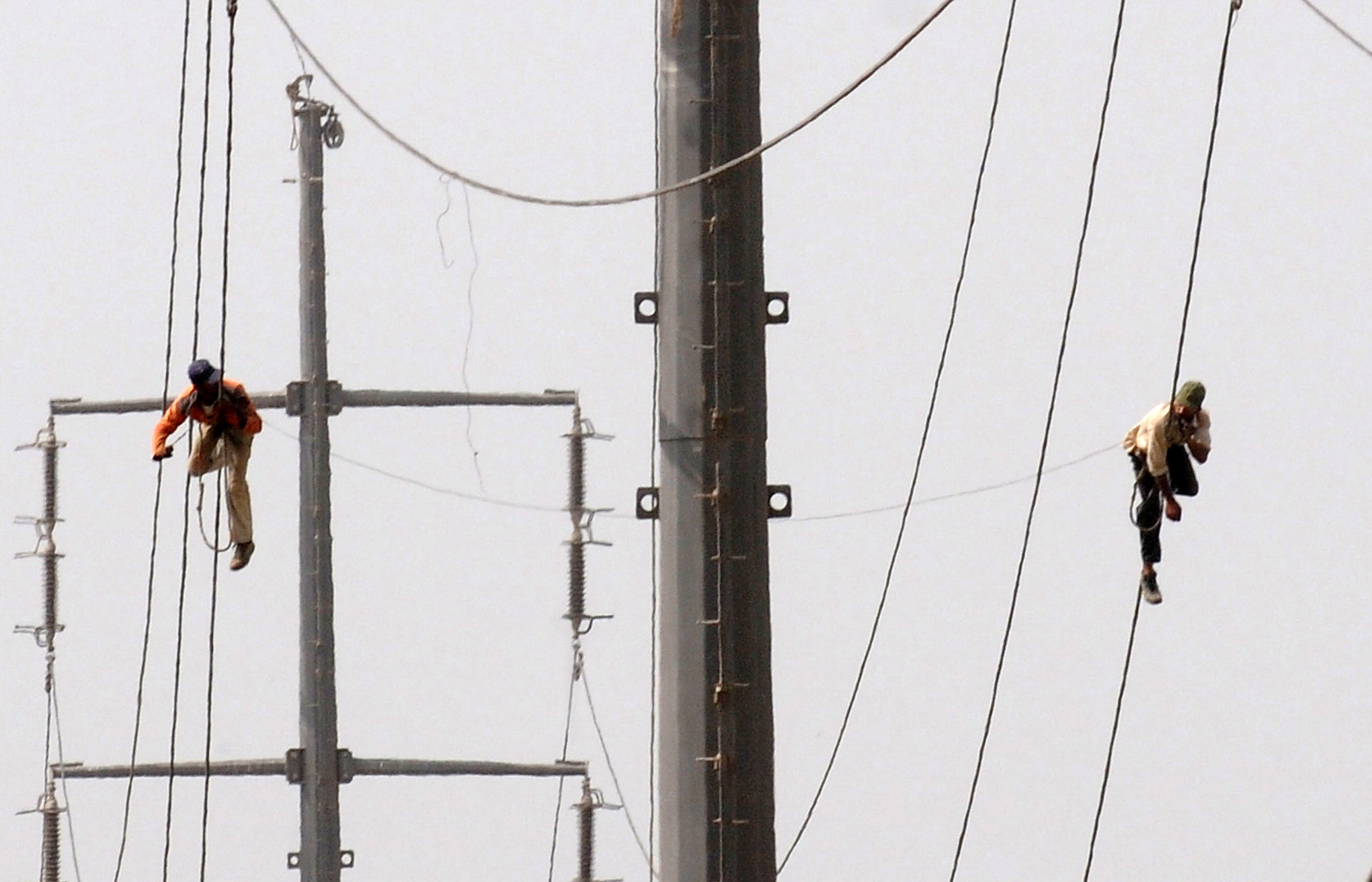 Pakistani technicians work on high voltage power lines in Karachi on Aug. 11, 2009. (AFP/File)