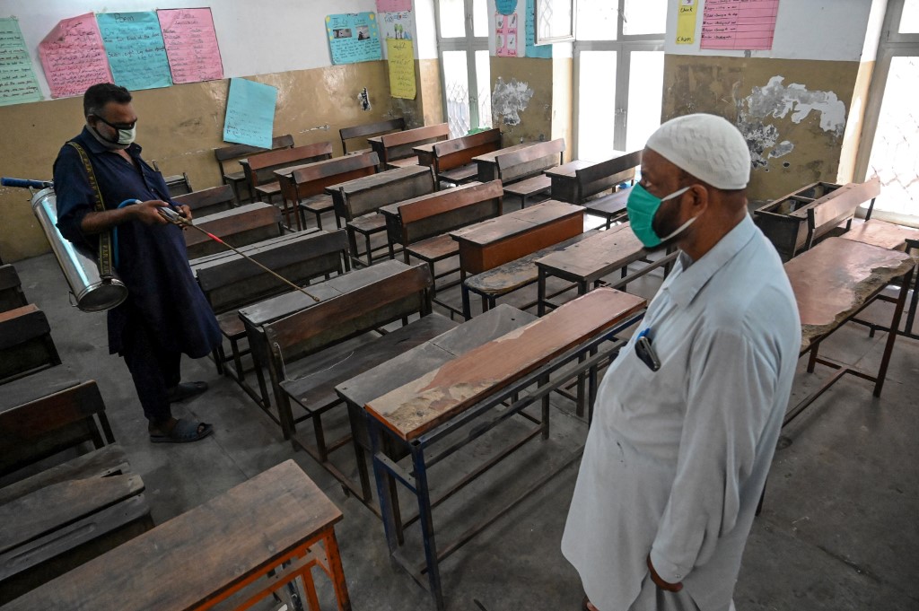A school worker sprays disinfectant in a classroom at a school in Lahore on Sept. 12, 2020, as the Pakistani government announced the reopening of education institutions from Sept. 15, after nearly a six-month closure due to the coronavirus pandemic. (AFP)