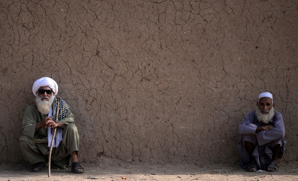 In this picture taken on October 18, 2018, older Afghan refugees sit outside their mud house at a refugee camp on the outskirts of Islamabad, Pakistan. (AFP/File)