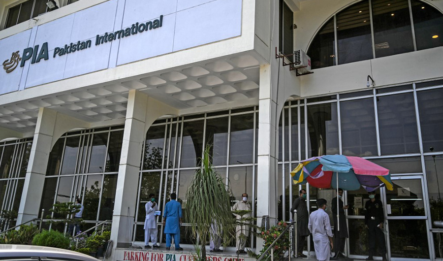 People stand in queue as they wait to buy flight tickets outside Pakistan International Airlines (PIA) office in Islamabad on July 1, 2020. (AFP)