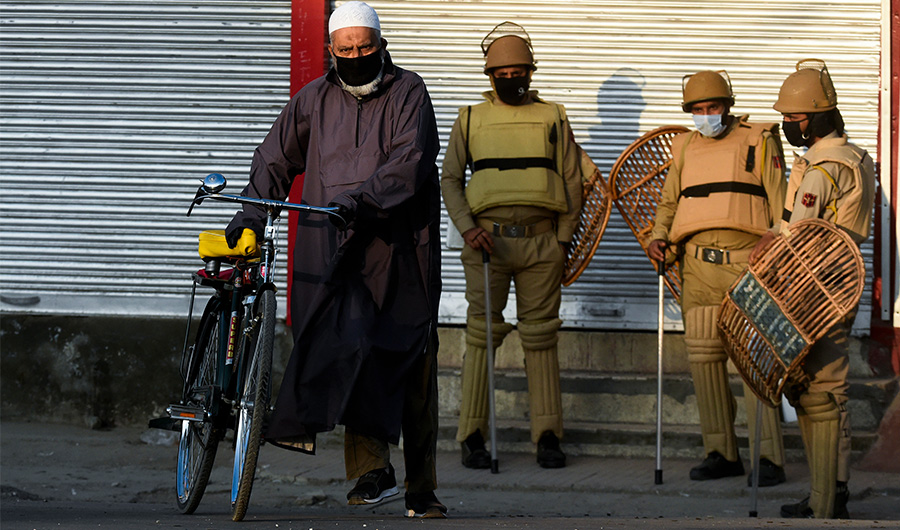 A man walks past policemen guarding an area near the site of a gun battle between suspected militants and government forces in downtown Srinagar on May 19, 2020. (AFP)