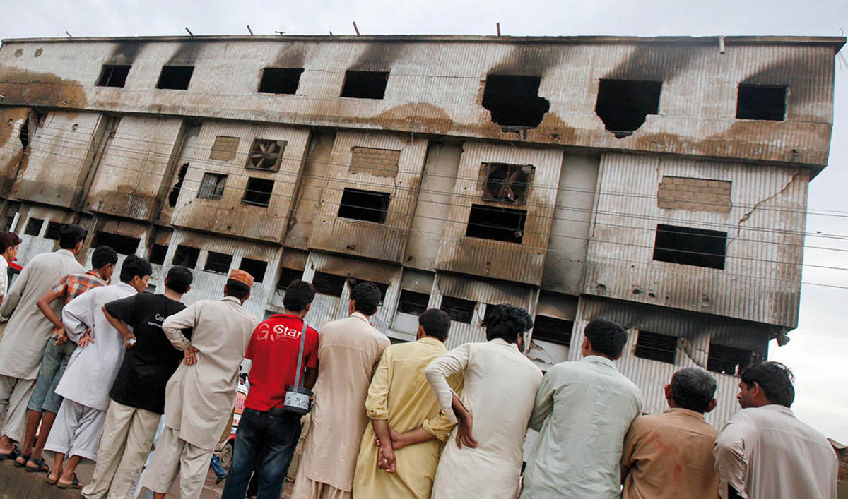 Residents stand outside a burnt garment factory in Karachi on Sept. 13, 2012. (REUTERS/File)