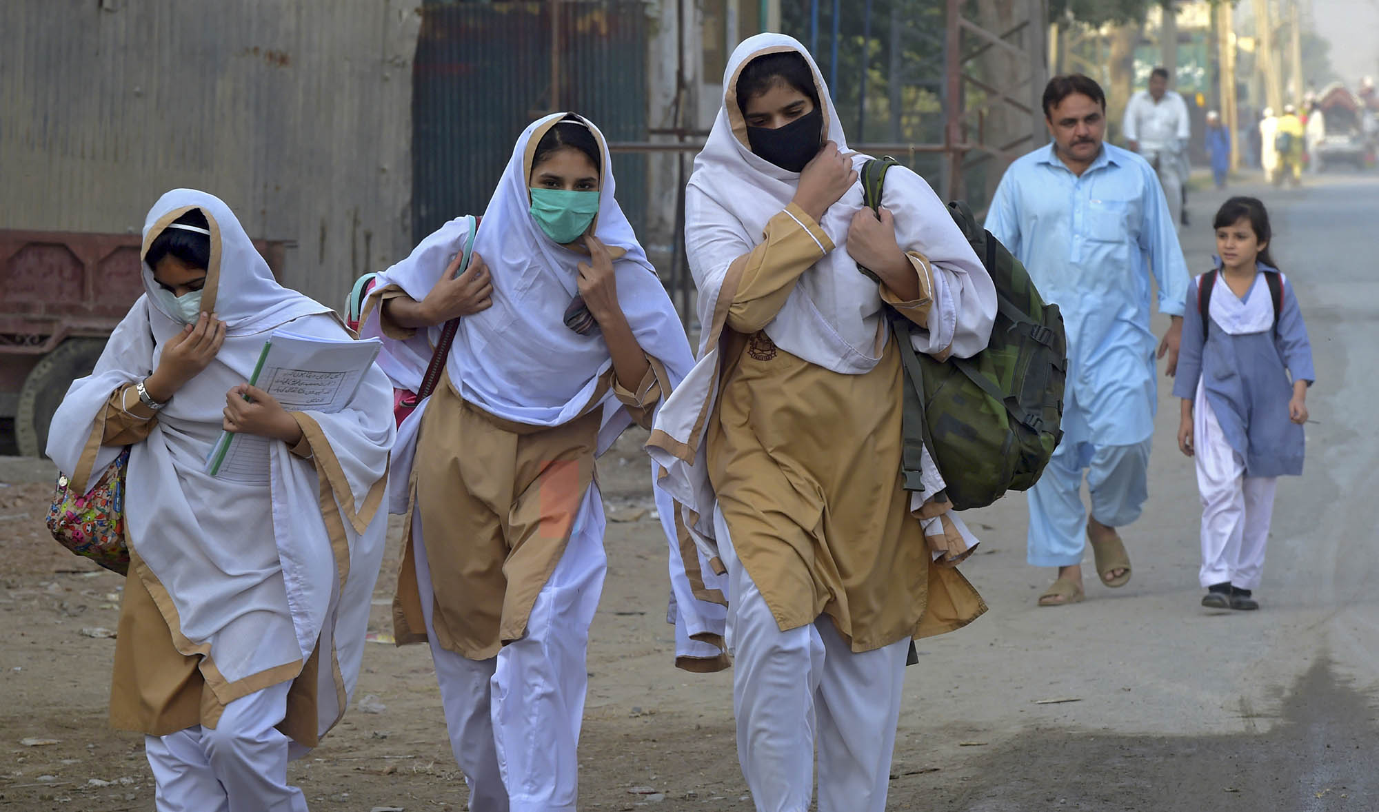 Students wearing facemasks walk through a street to their school in Peshawar on Sept. 15, 2020 after the educational institutes were reopened nearly six months after the spread of the Covid-19 coronavirus. (AFP/File)