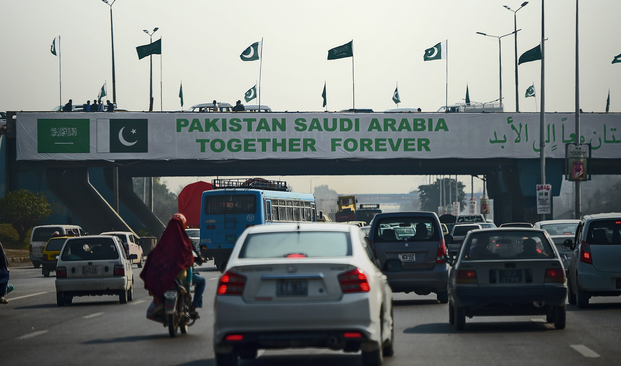 Pakistani commuters drive their vehicles under a banner welcoming Saudi Arabian Crown Prince Mohammed bin Salman displayed on a bridge, ahead of his arrival, in Islamabad on Feb. 15, 2019. (AFP/File)