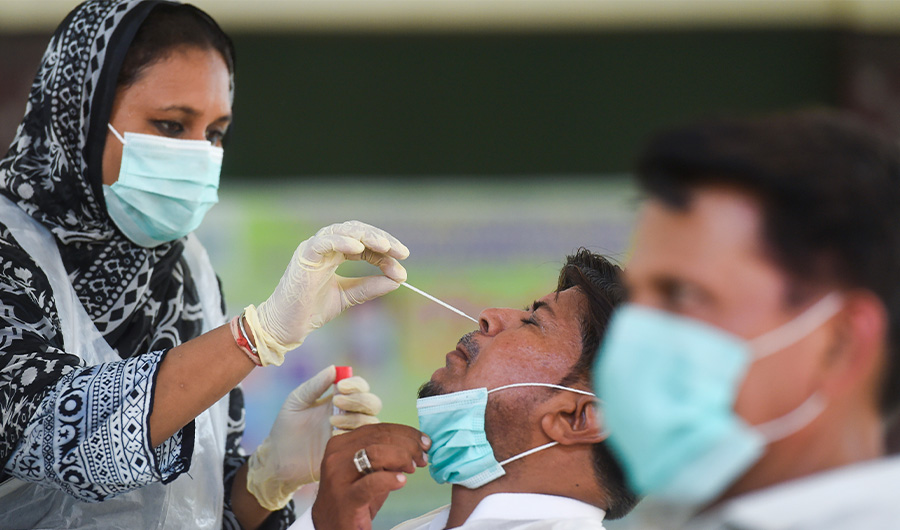 A health official collects a swab sample from a teacher to test for the COVID-19 coronavirus at a government school following the government's announcement to reopen educational institutes starting from September 15, in Karachi on September 14, 2020. (AFP)