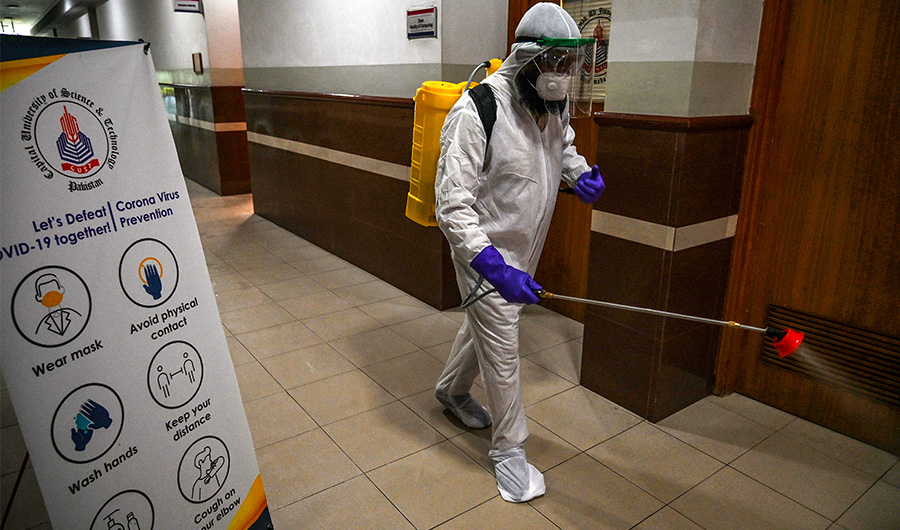 A worker wearing a Personal Protective Equipment (PPE) suit sprays disinfectant at the Capital University of Science and Technology in Islamabad on September 10, 2020. (AFP)