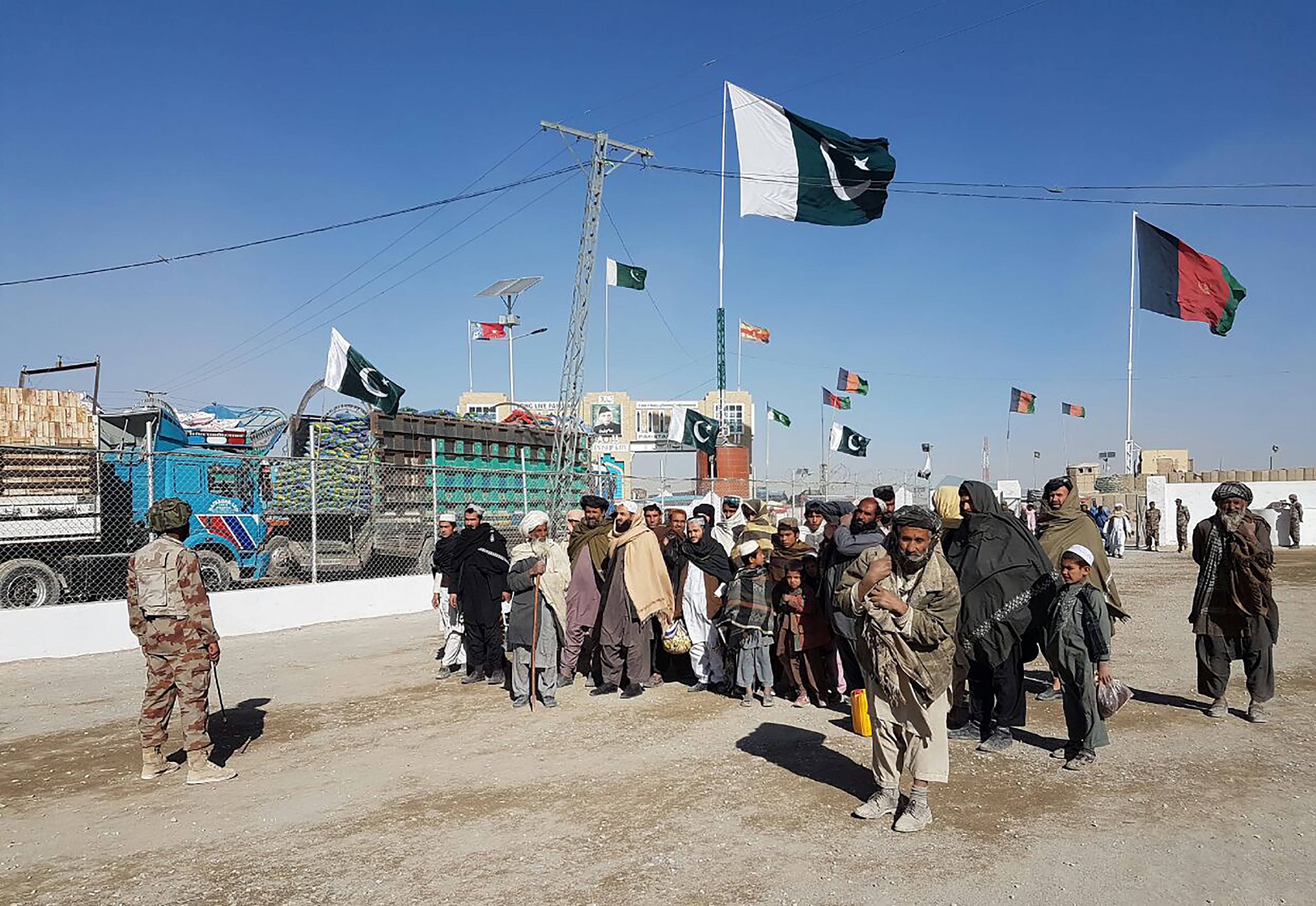 In this photograph taken on January 7, 2017, travellers are watched by Pakistan security personnel as they wait to cross the border between Pakistan and Afghanistan at Chaman. (AFP)