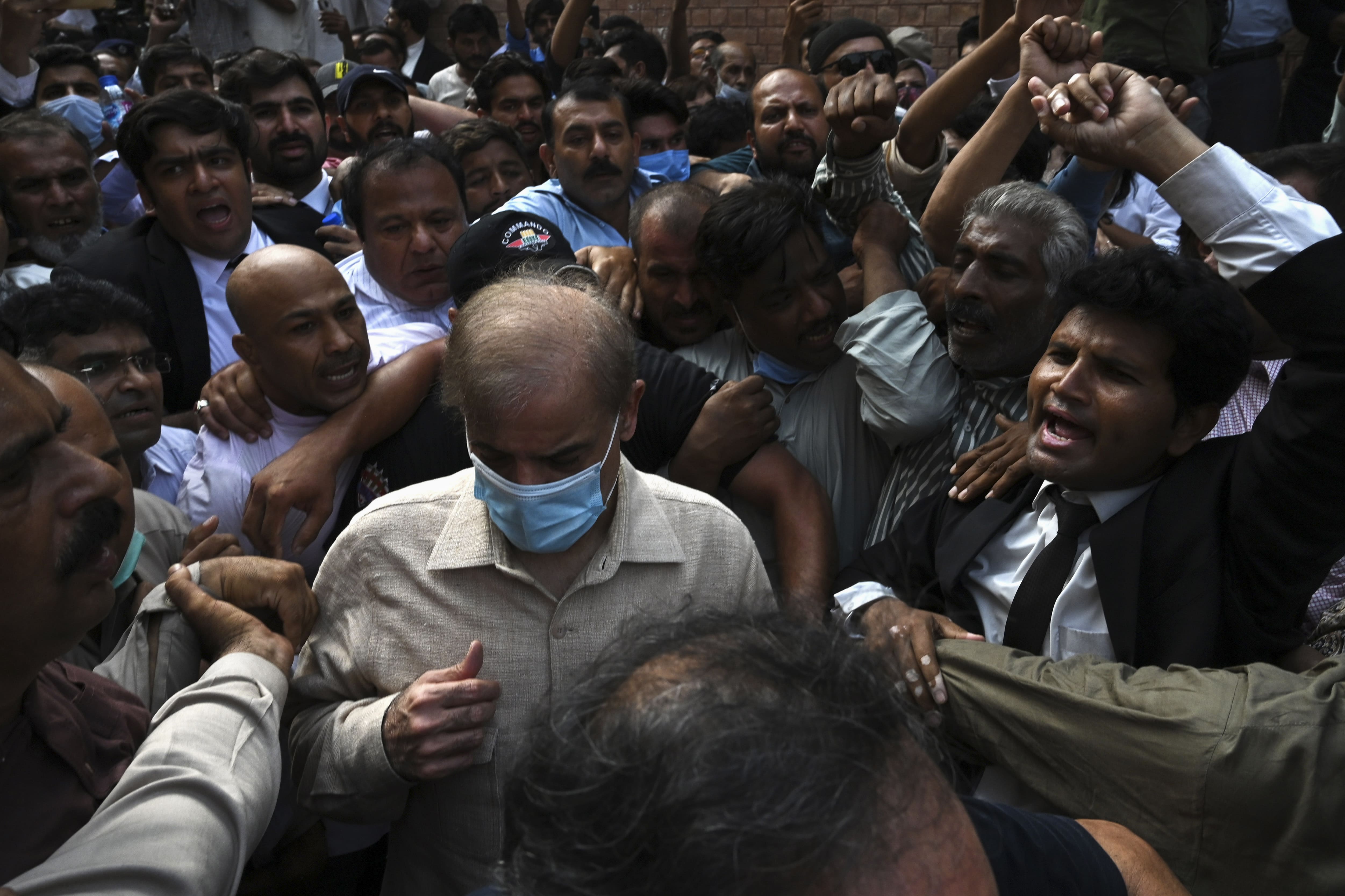 Shahbaz Sharif (C wearing mask), Pakistani opposition leader and brother of former prime minister Nawaz Sharif, comes out from the high court surrounded by supporters after the court rejected his bail plea in a money laundering and assets beyond income case, in Lahore on September 28, 2020. (AFP)