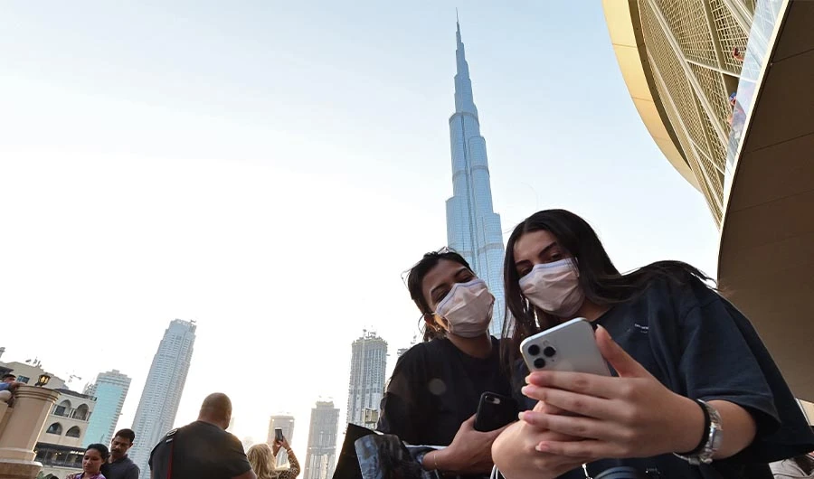 Women wearing protective masks pose for a "selfie" picture on a cell phone in front of Burj Khalifa, the tallest structure and building in the world since 2009 (total heigh with antenna of 829.8 metres), in the city centre of the Gulf emirate of Dubai on March 8, 2020. (AFP)