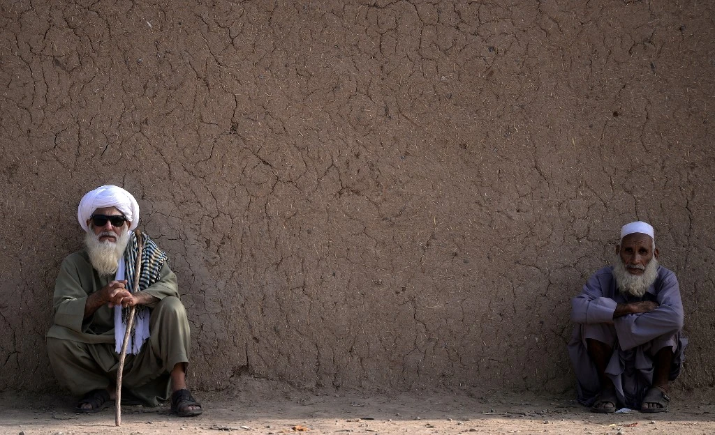 In this picture taken on October 18, 2018, older Afghan refugees sit outside their mud house at a refugee camp on the outskirts of Islamabad, Pakistan. (AFP/File)