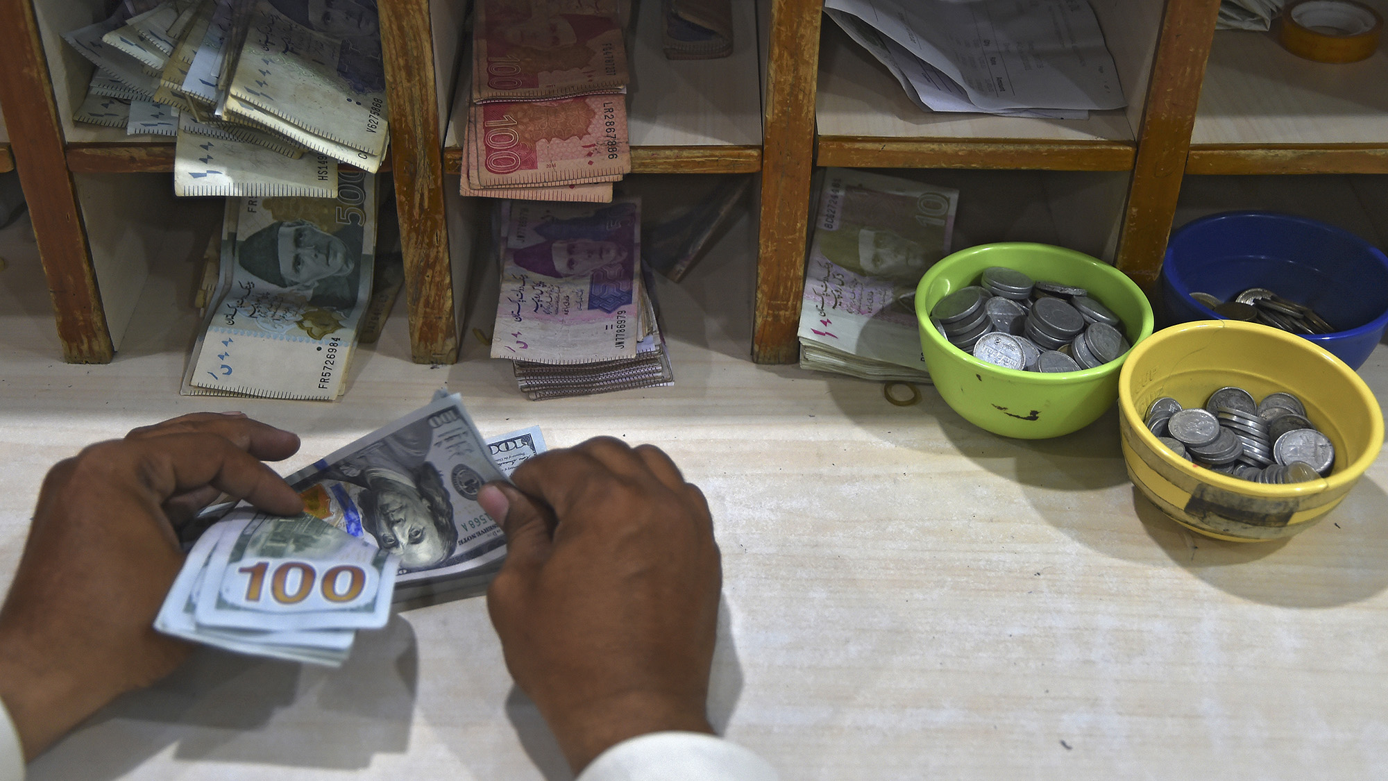 In this picture taken on July 22, 2019, a foreign currency dealer counts US dollar notes at a shop in Karachi. (AFP/File)