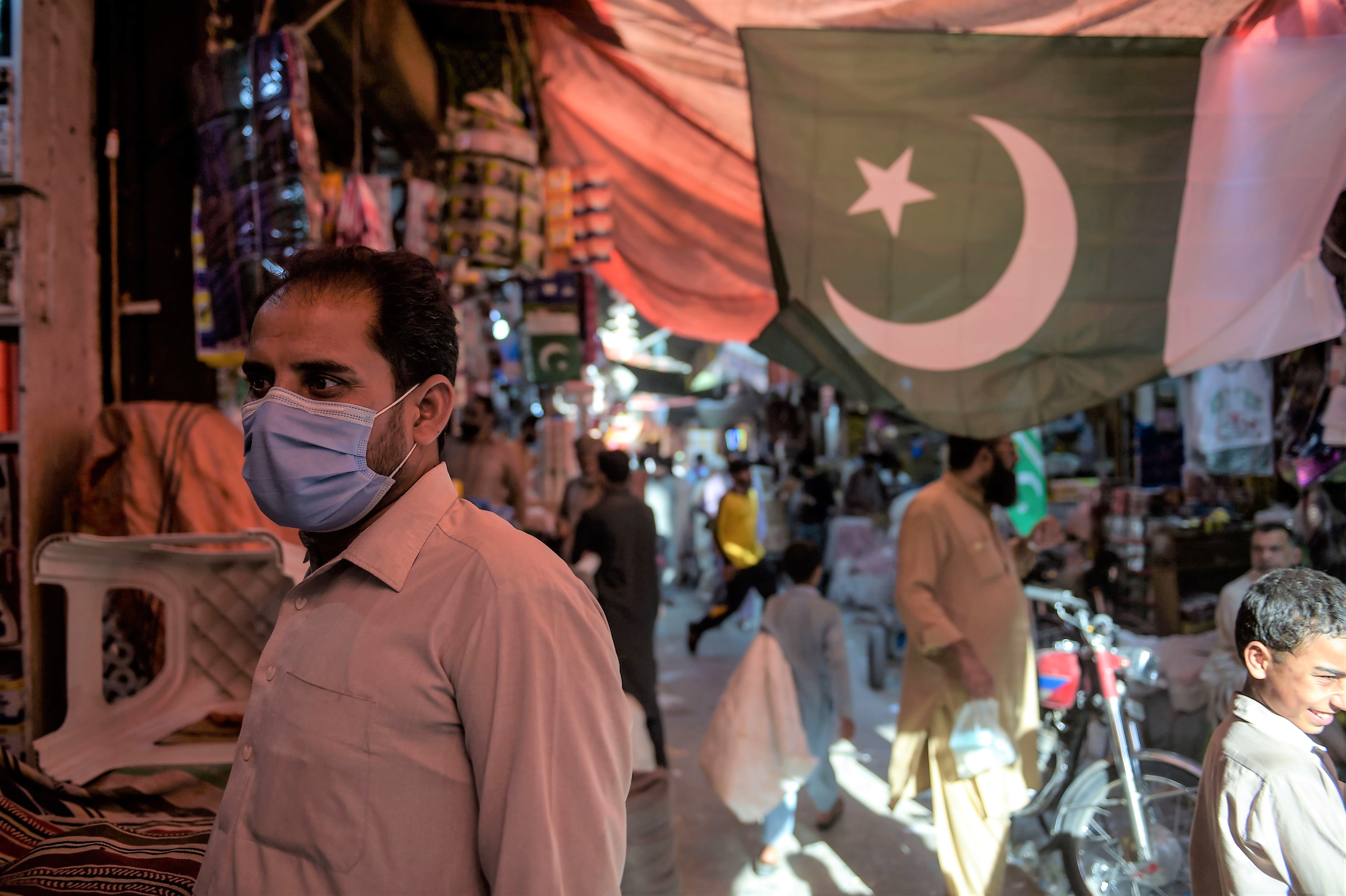 In this picture taken on July 22, 2020, a man wearing a face mask as a preventive measure against the COVID-19 coronavirus shops at the Raja Bazar in Rawalpindi. (AFP)