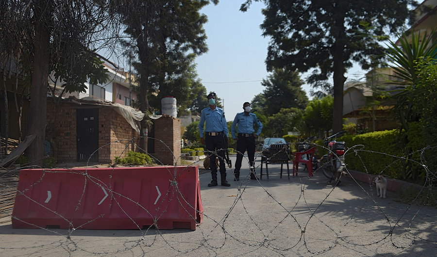 Pakistani policemen wearing facemasks stand guard in front of a cordoned off area after some residents tested positive for Covid-19 coronavirus, in Islamabad on October 11, 2020. (AFP)
