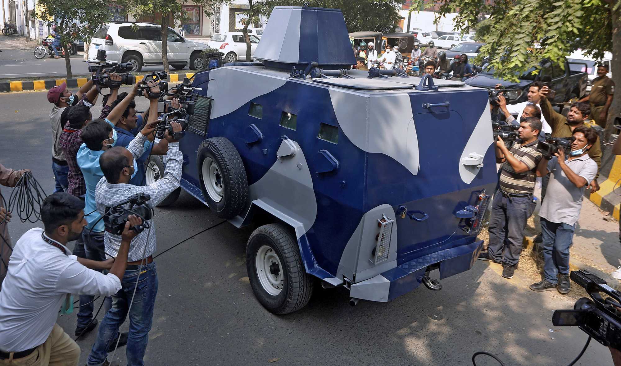 Video journalists film an armored vehicle carrying Abid Malhi, a key assailant suspected in the gang rape of a woman on a desolate highway, following his court appearance in Lahore on Oct. 13, 2020. (AP)