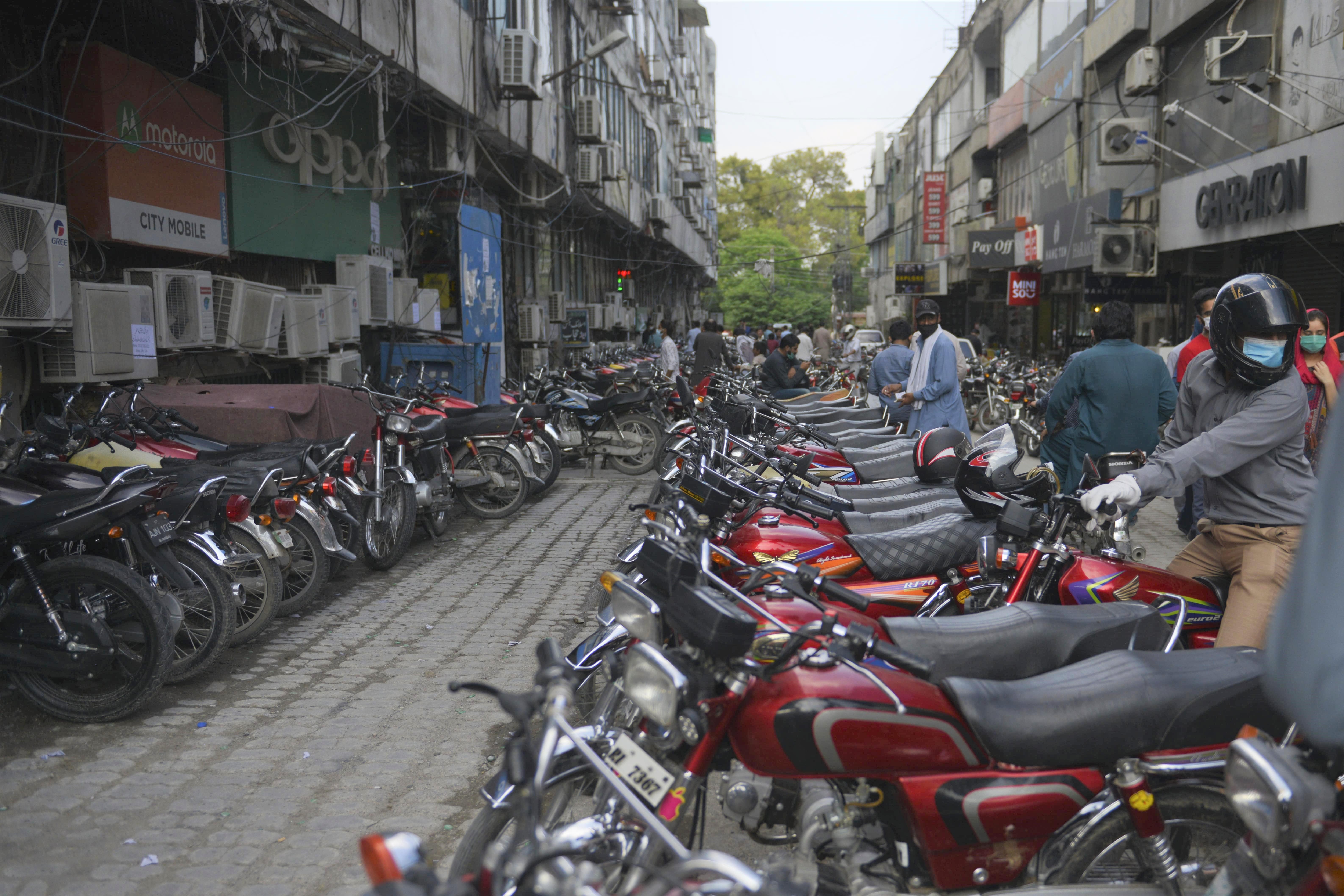 A man sits on his motorbike as he leaves from a mobile phone market in Rawalpindi on June 1, 2020. (AFP)