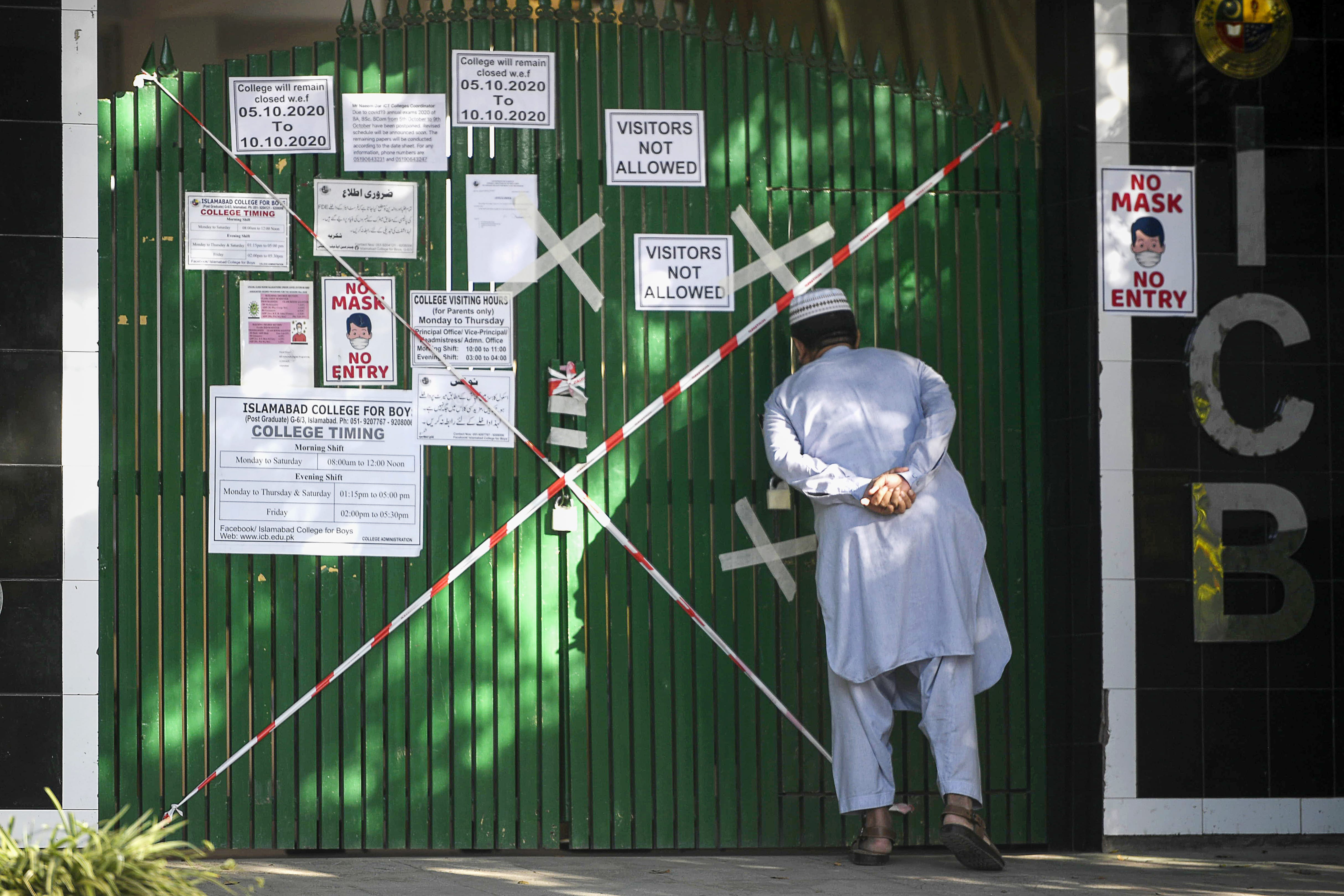 A man looks inside from a closed gate of a school sealed by authorities as some teachers and students tested positive for the Covid-19 Coronavirus in Islamabad on October 5, 2020. (AFP)