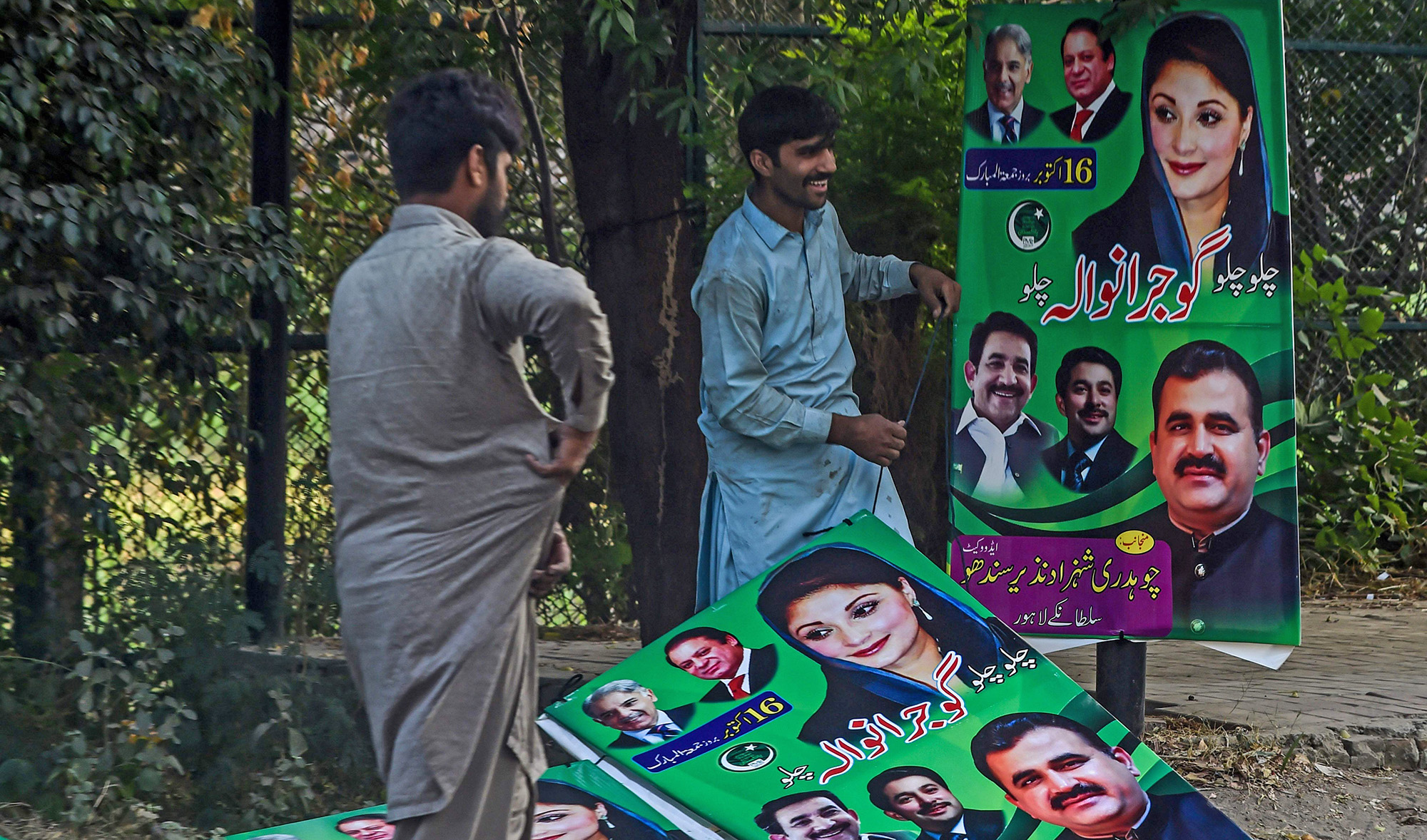 Workers hang posters of opposition party Pakistan Muslim League Nawaz (PML-N) on a street in Lahore on Oct. 15, 2020, as part of preparations ahead of an opposition rally. (AFP)